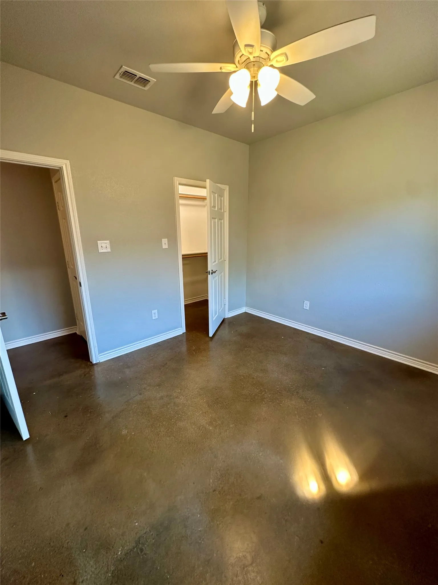 Featuring finished concrete flooring, a ceiling fan, and baseboards