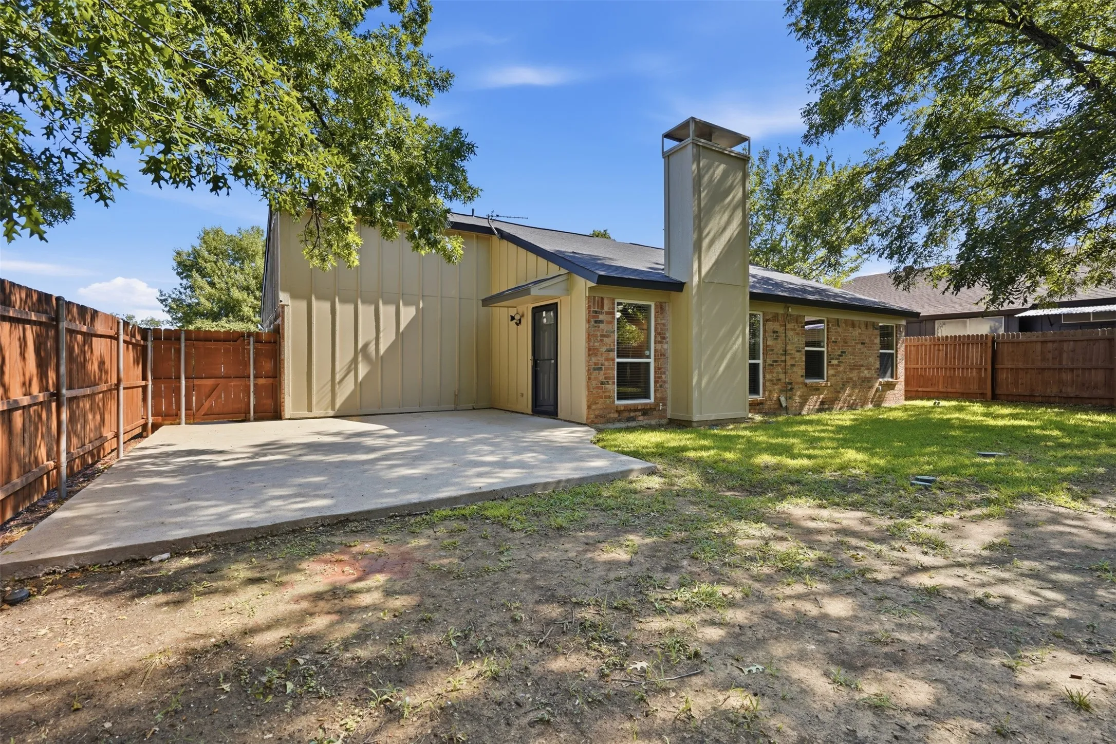 Rear exterior featuring a concrete patio, brick and siding facade, and multiple windows