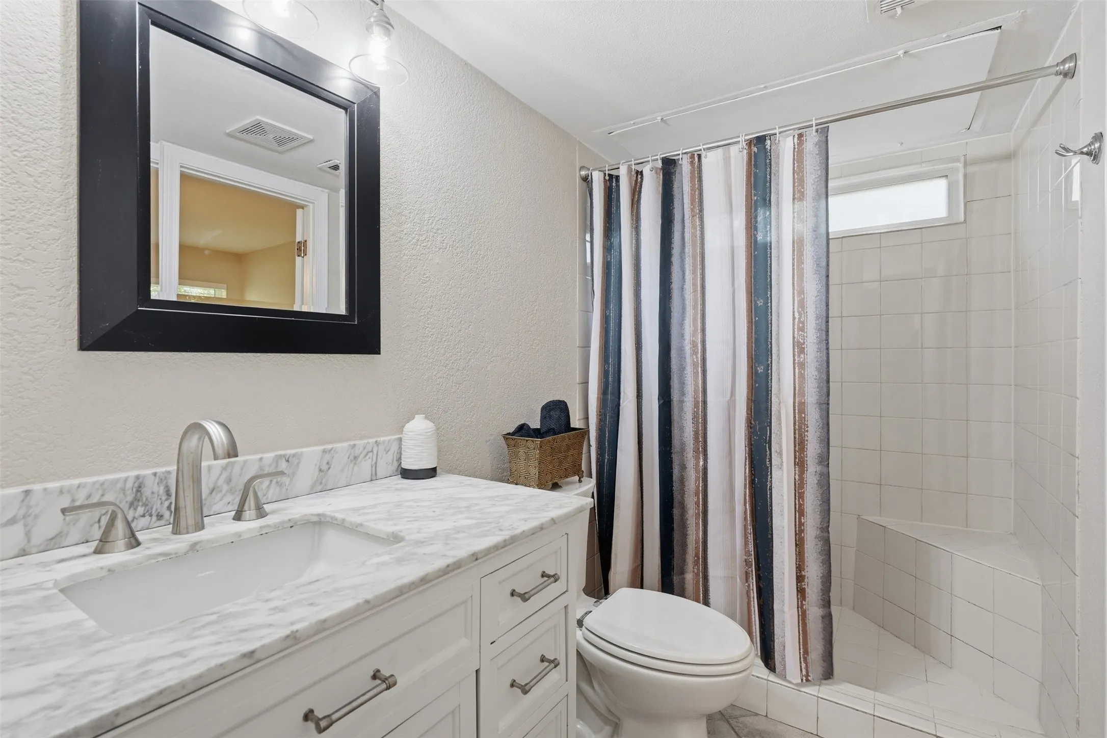 White vanity with a light marble-patterned countertop, under-mount sink, and brushed nickel fixtures
