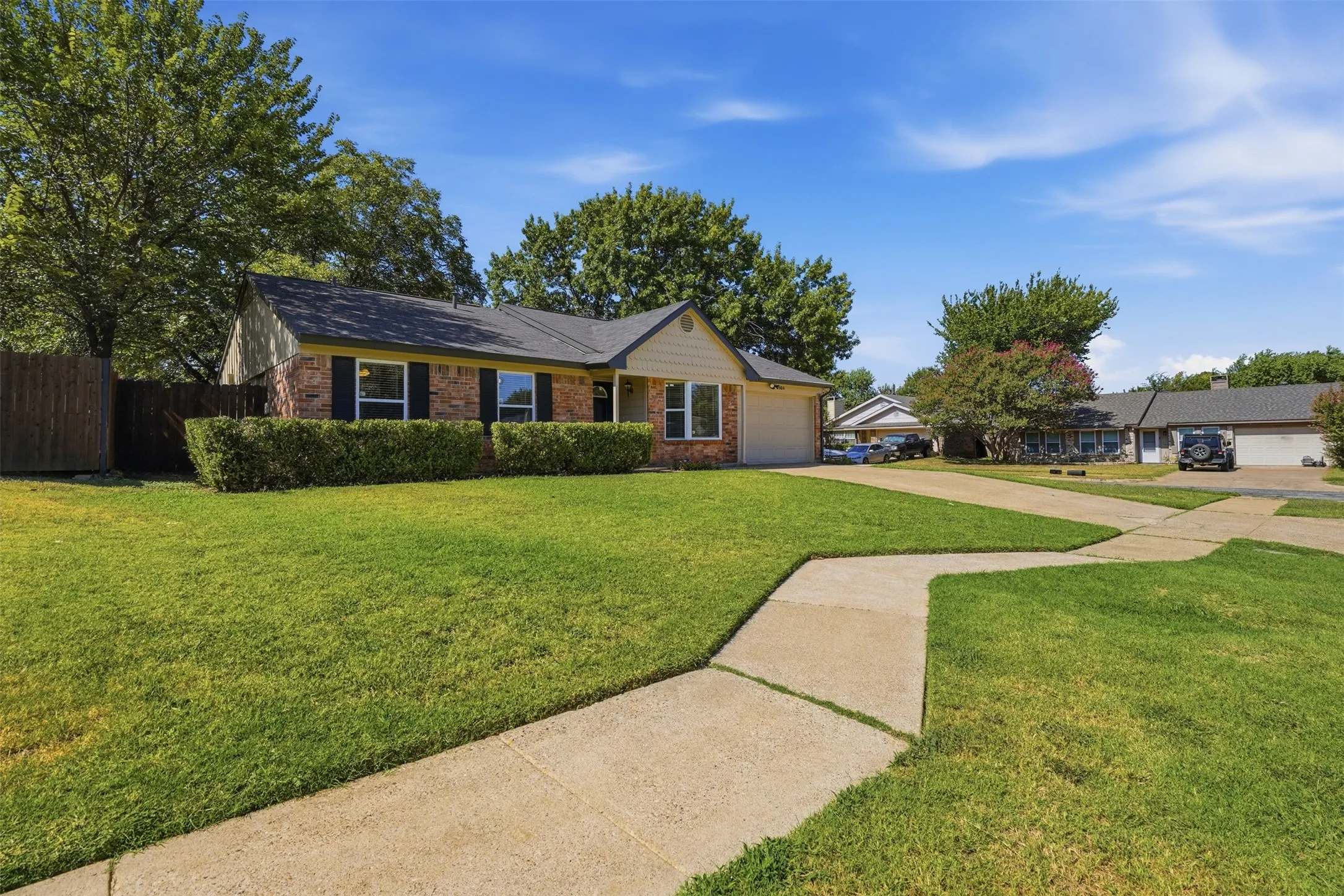 Brick facade residence featuring a dark shingle roof, attached garage, and a concrete driveway