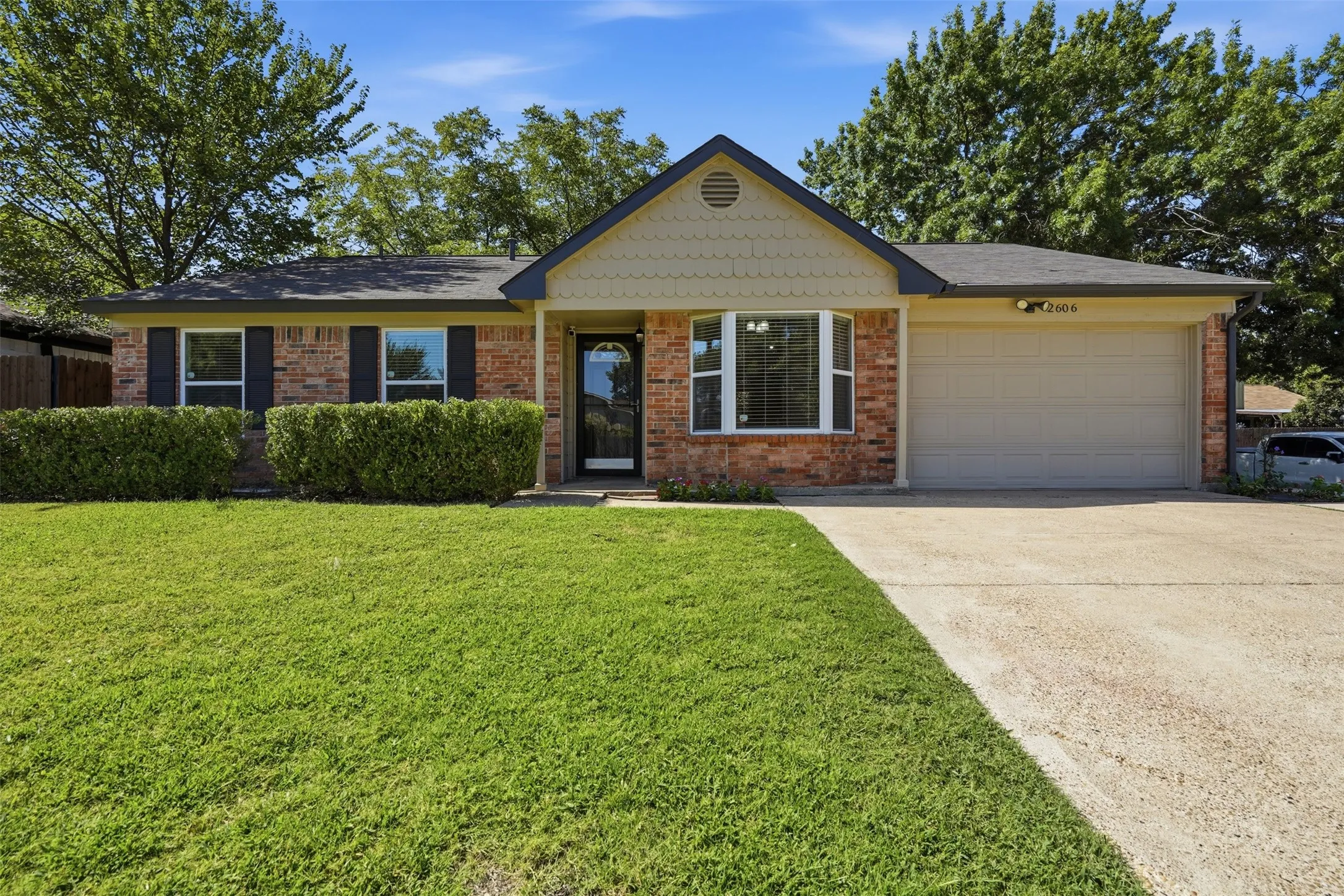 Single-story exterior with brick and siding facade, covered entry, attached garage, and a concrete pathway