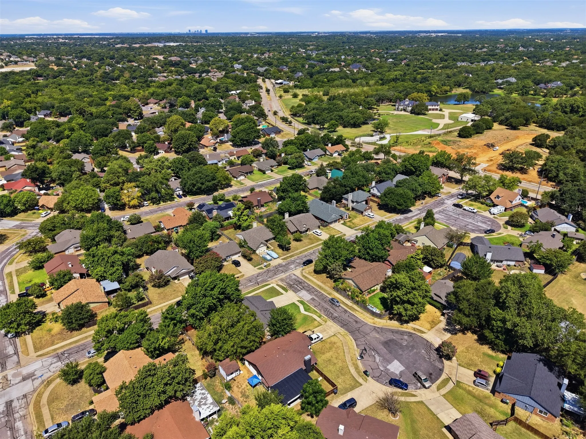 Expansive neighborhood featuring mature trees, residential properties, and paved roadways