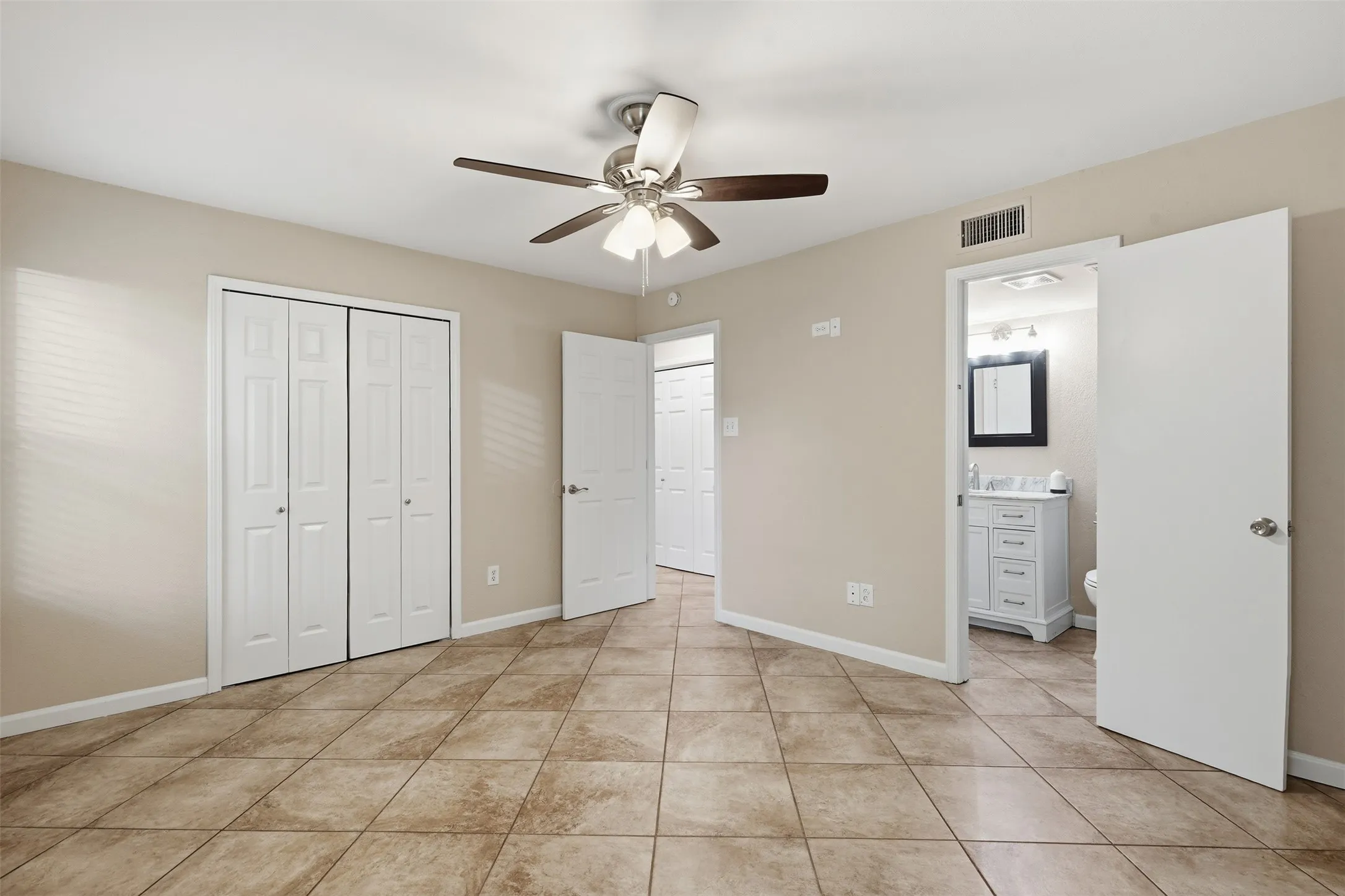 Ceramic tile flooring, neutral wall tones, bi-fold closet doors, and a ceiling fan with integrated lighting