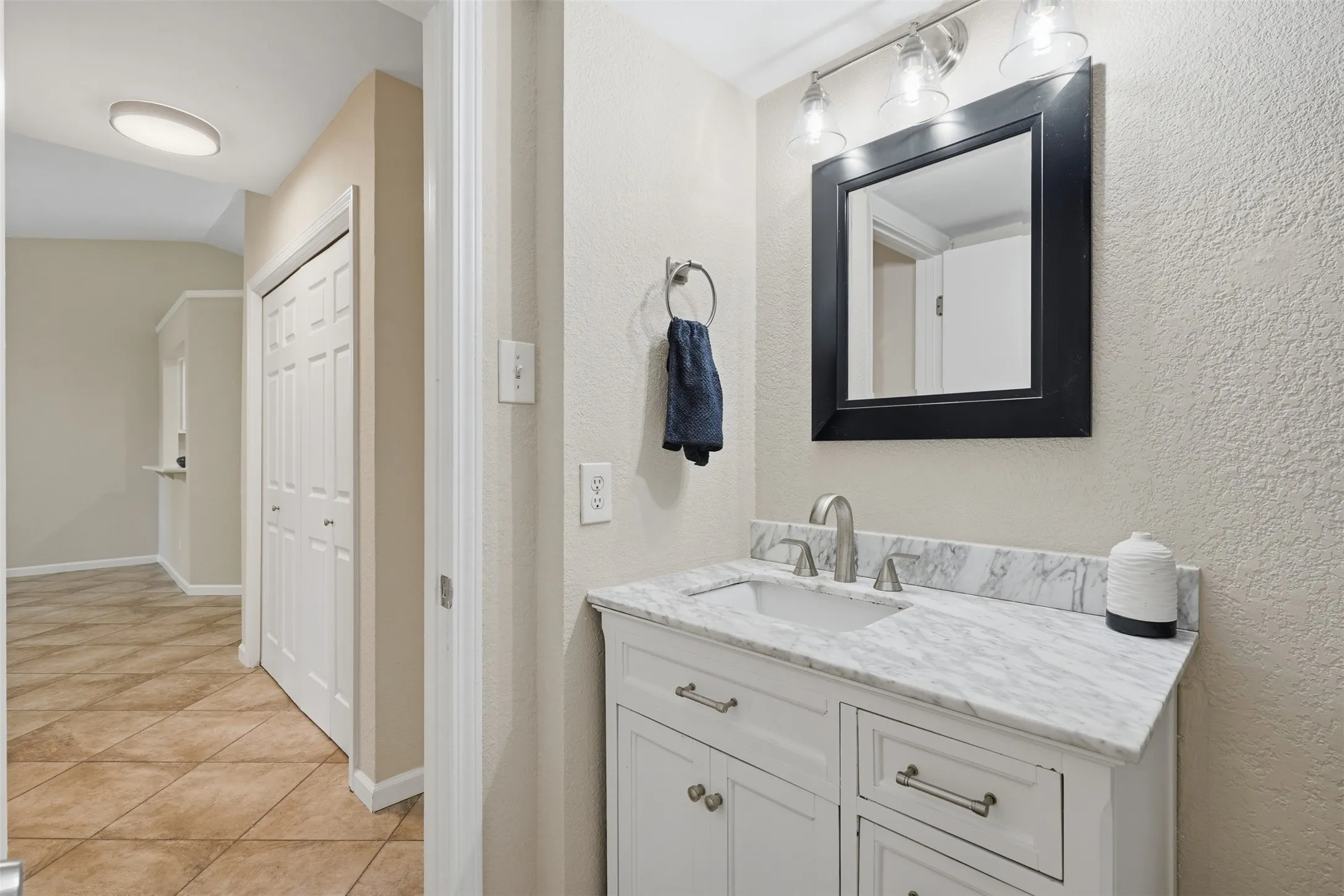 White vanity with integrated sink, stone-finish countertop, and brushed nickel faucet