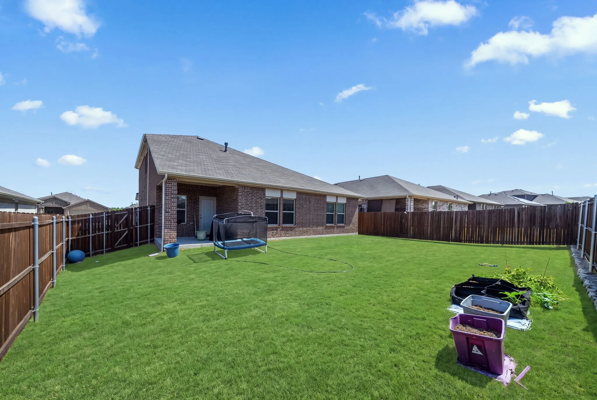 Expansive backyard with lush, manicured lawn bordered by wood-finish fencing