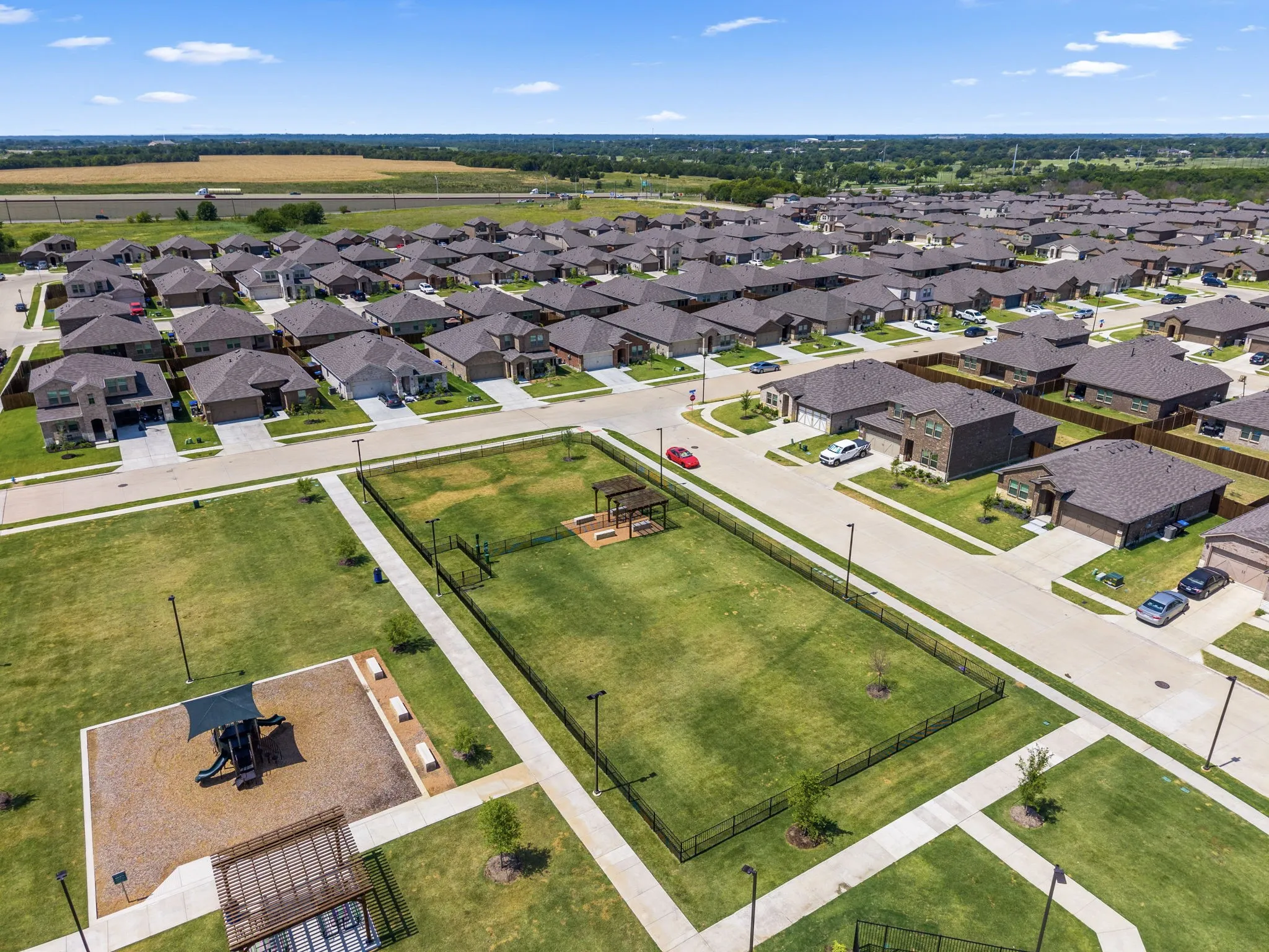 Spacious residential community featuring newly constructed homes with dark architectural rooflines, manicured lawns, and paved streets