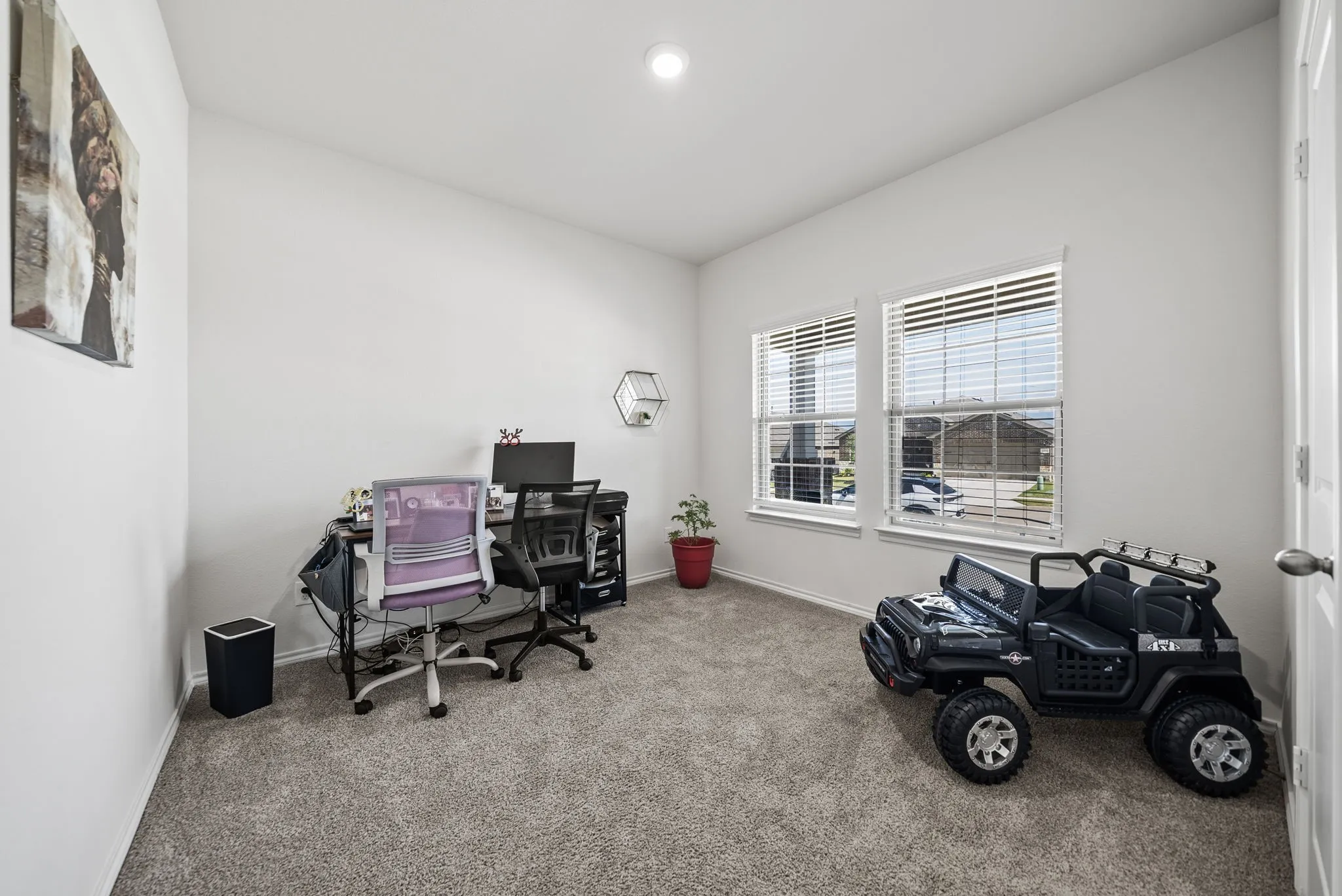 Bright, versatile office space featuring neutral carpeting, abundant natural light from dual windows with plantation shutters, recessed ceiling lighting, and ample room for work stations and storage