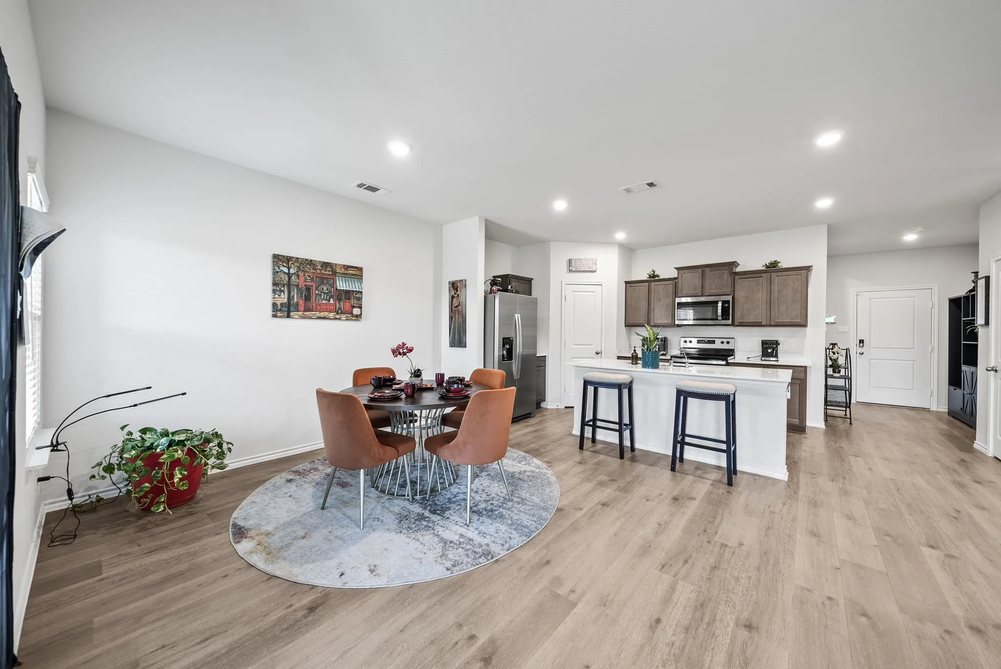 Open-concept living space featuring wood-finish flooring, recessed lighting, and a kitchen island with seating