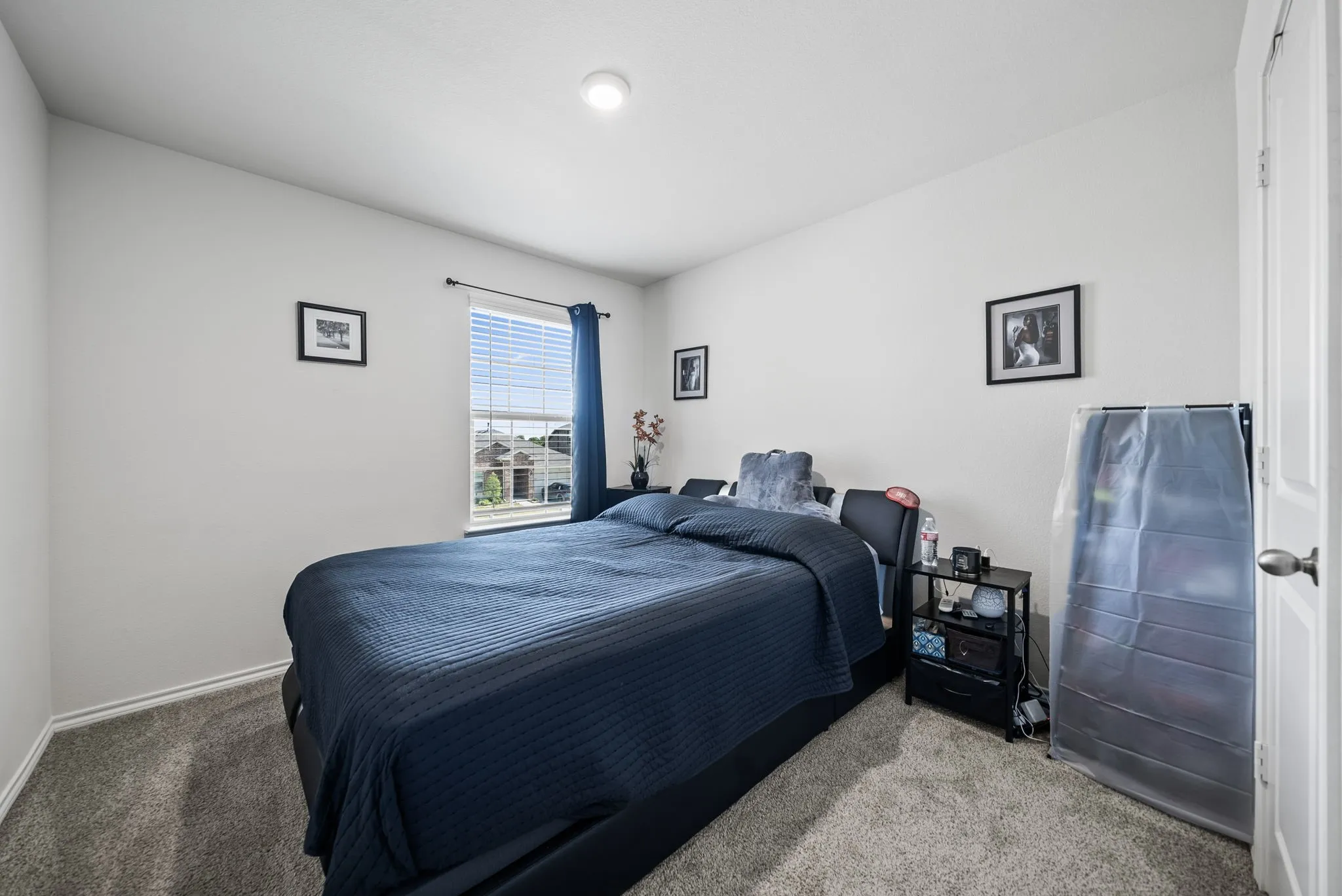 Spacious secondary bedroom featuring carpet flooring, recessed ceiling lighting, large window with blue drapery, and ample closet storage