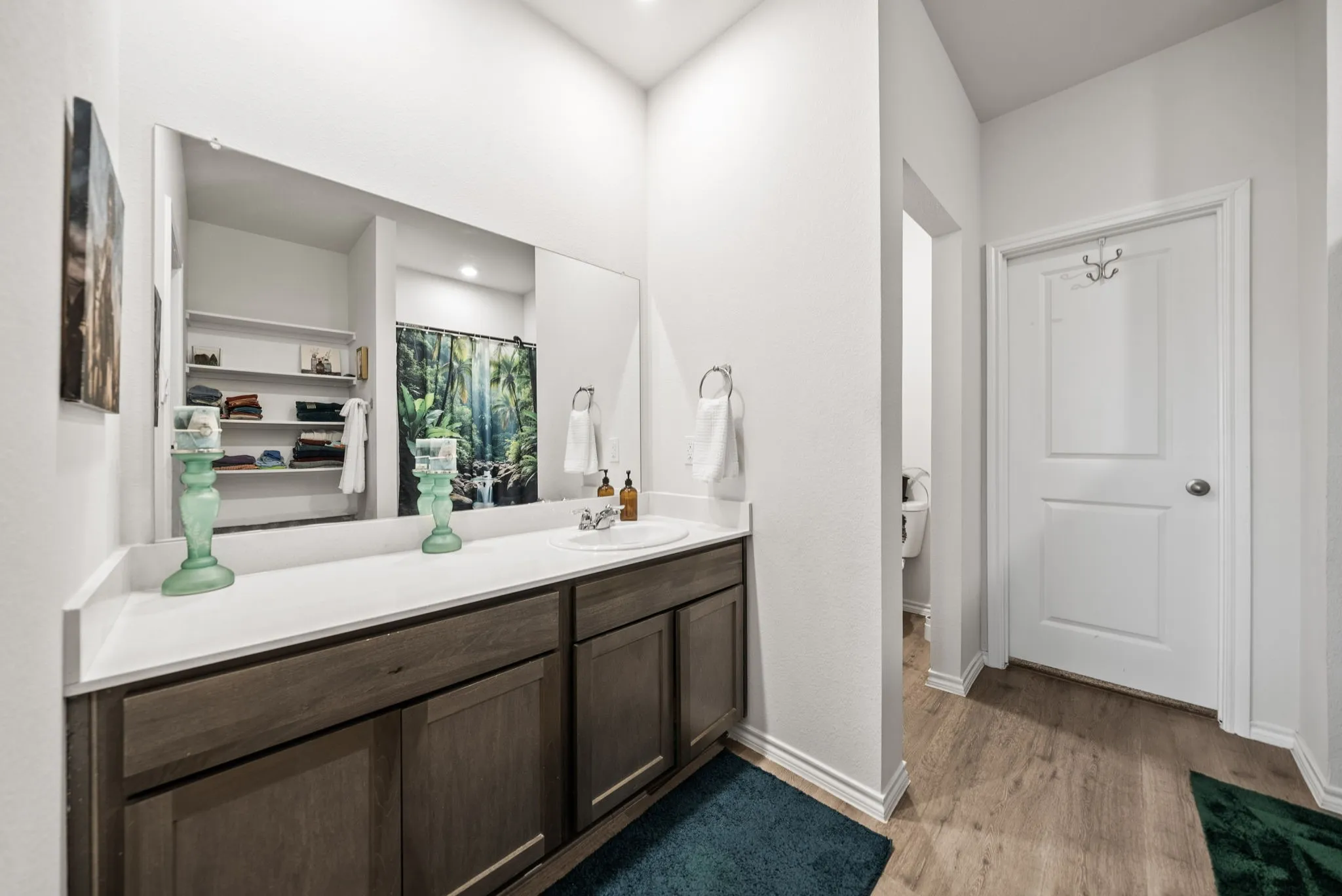 Spacious vanity with a light-toned countertop, wood-finish cabinetry, and a large wall-mounted mirror
