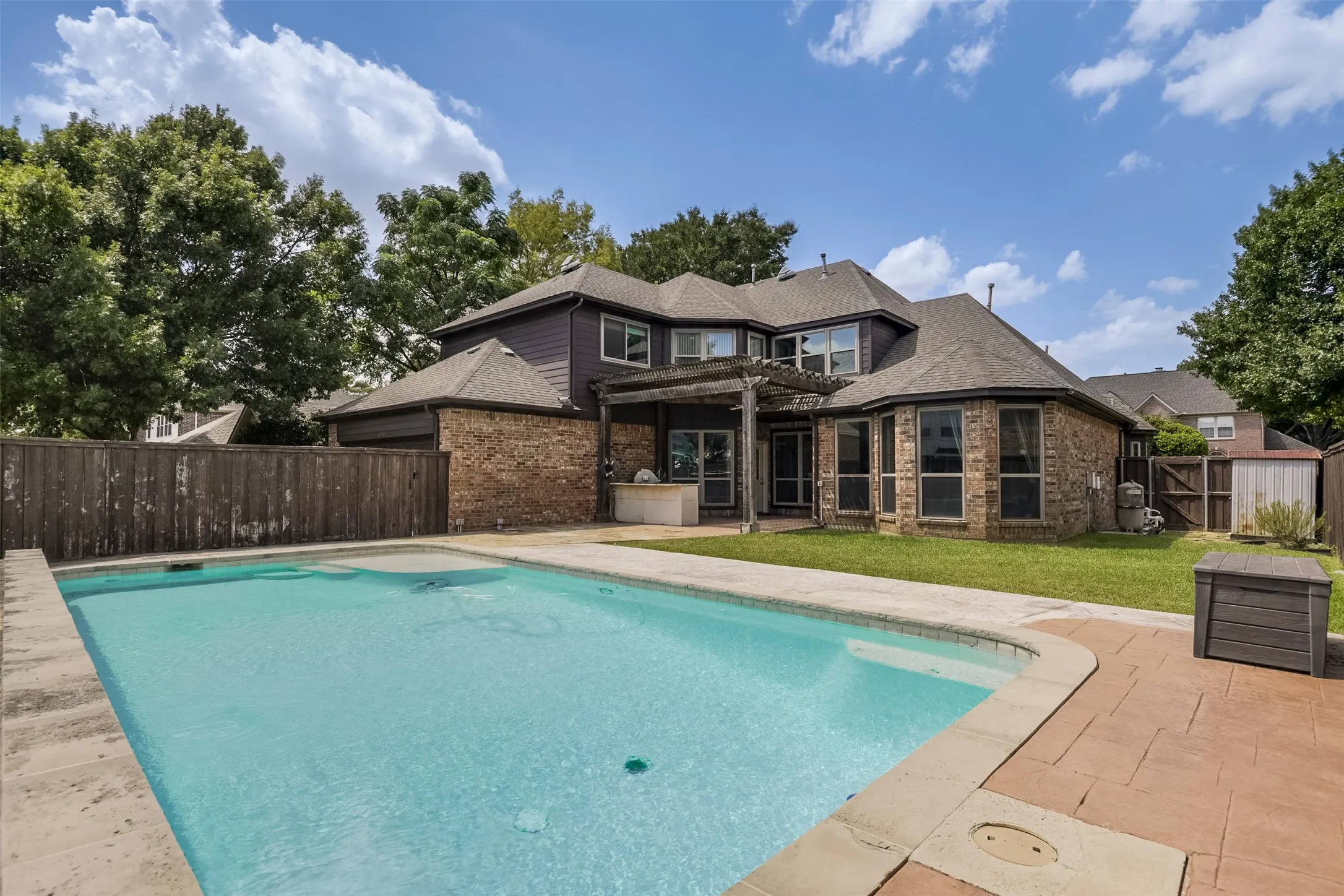 Expansive backyard with a rectangular swimming pool, concrete pool decking, and stamped concrete patio