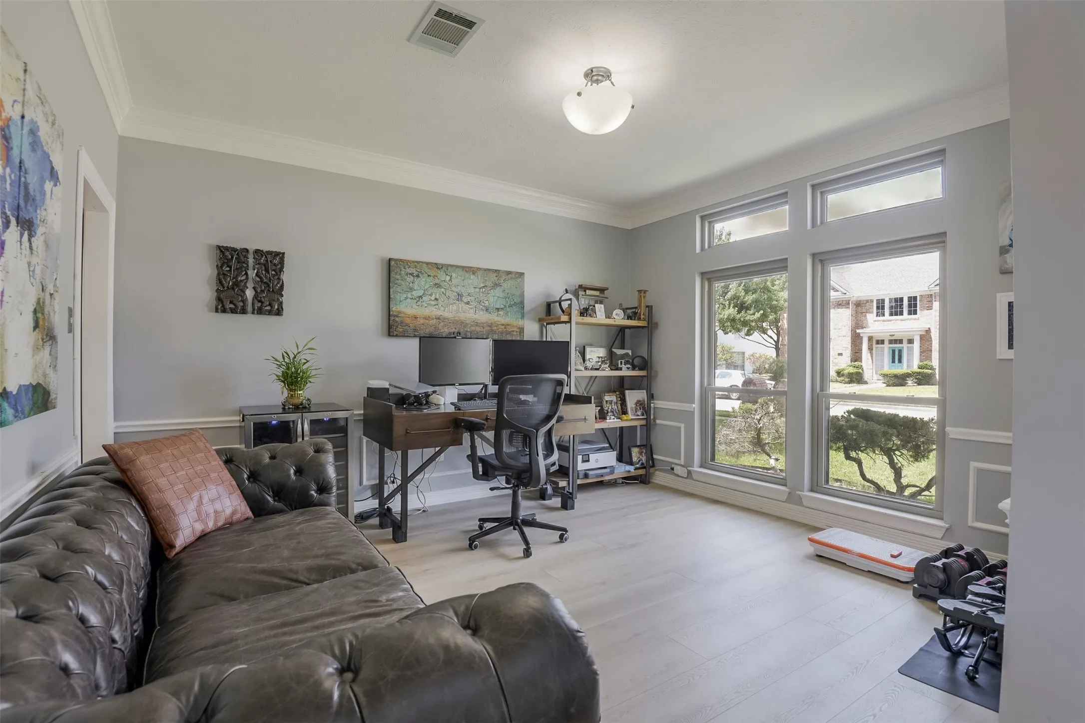 Light wood-finish flooring, extensive window array with transom windows, crown molding, chair rail molding, and a flush mount ceiling light fixture