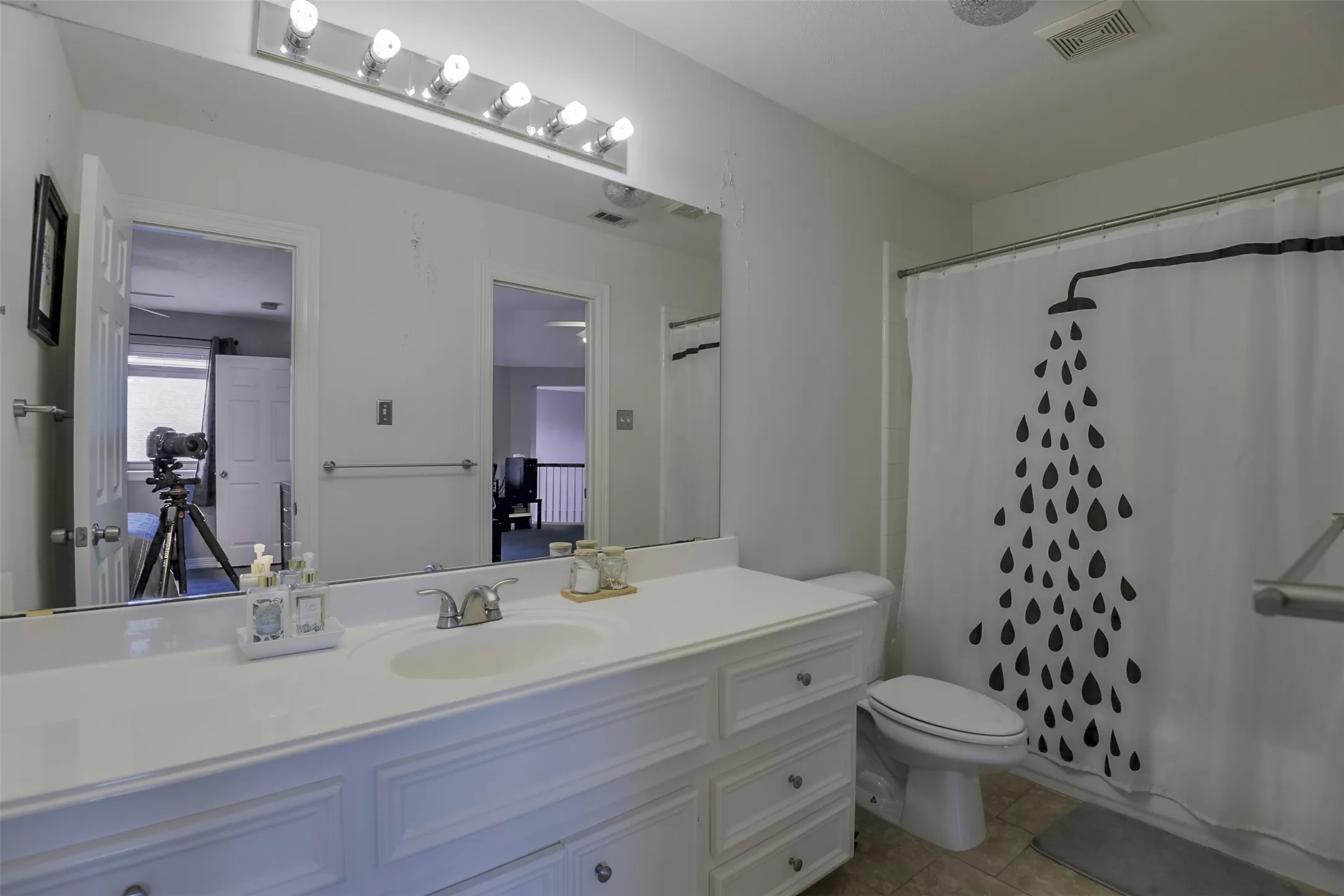 Bathroom with an integrated vanity sink, white cabinetry, a large wall-mounted mirror, and a shower-tub combination