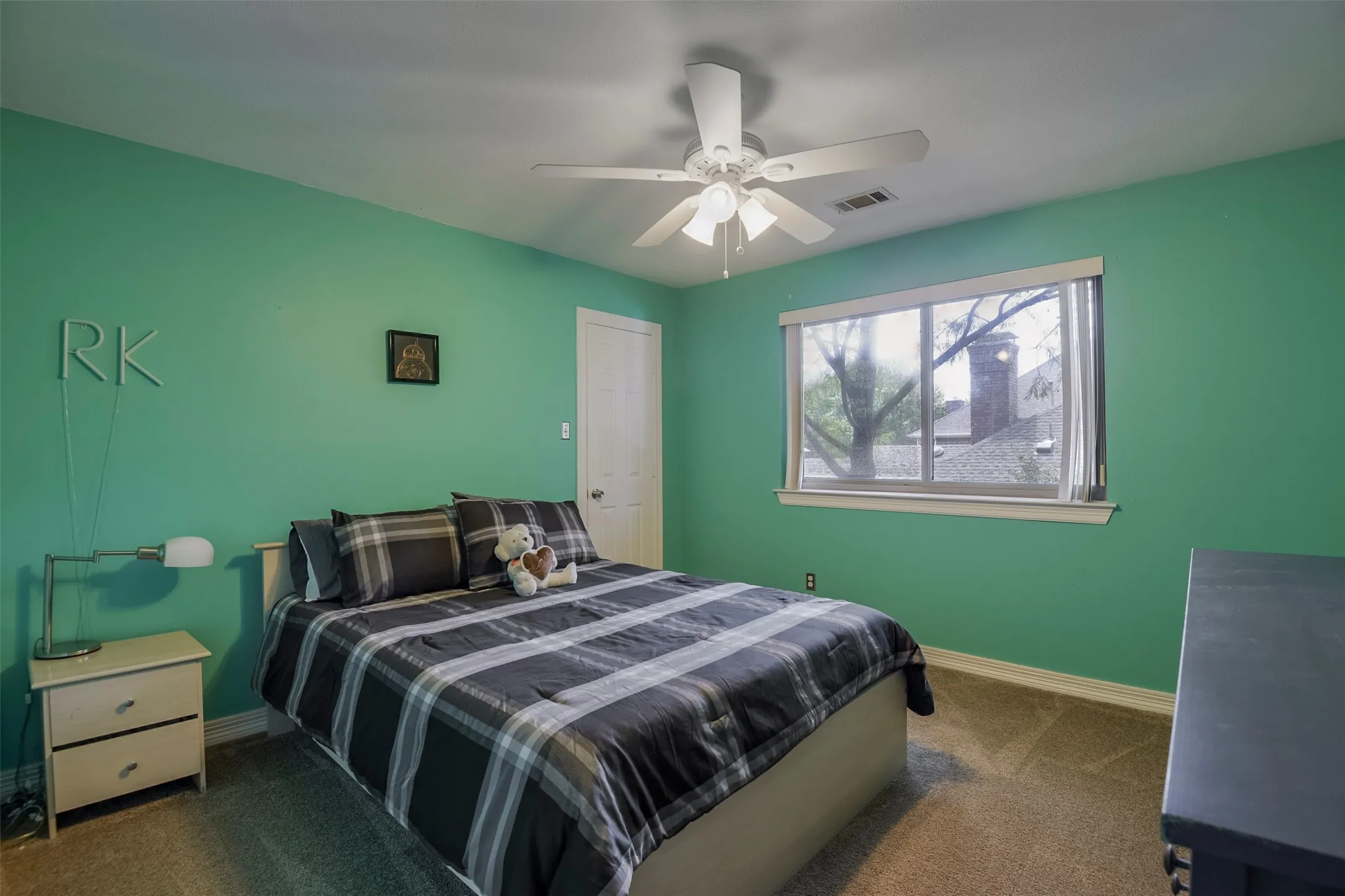 Recessed window with white trim, ceiling fan, white paneled door, and neutral-toned carpeting