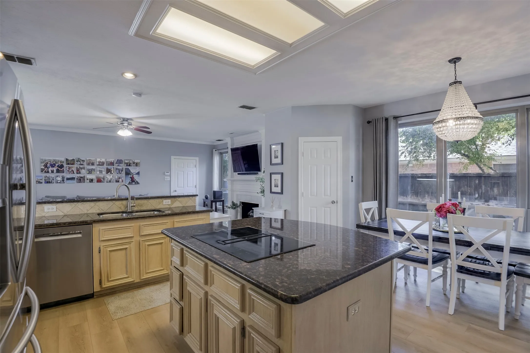 Kitchen island with a cooktop, stone countertops, stainless steel appliances, and a coffered ceiling