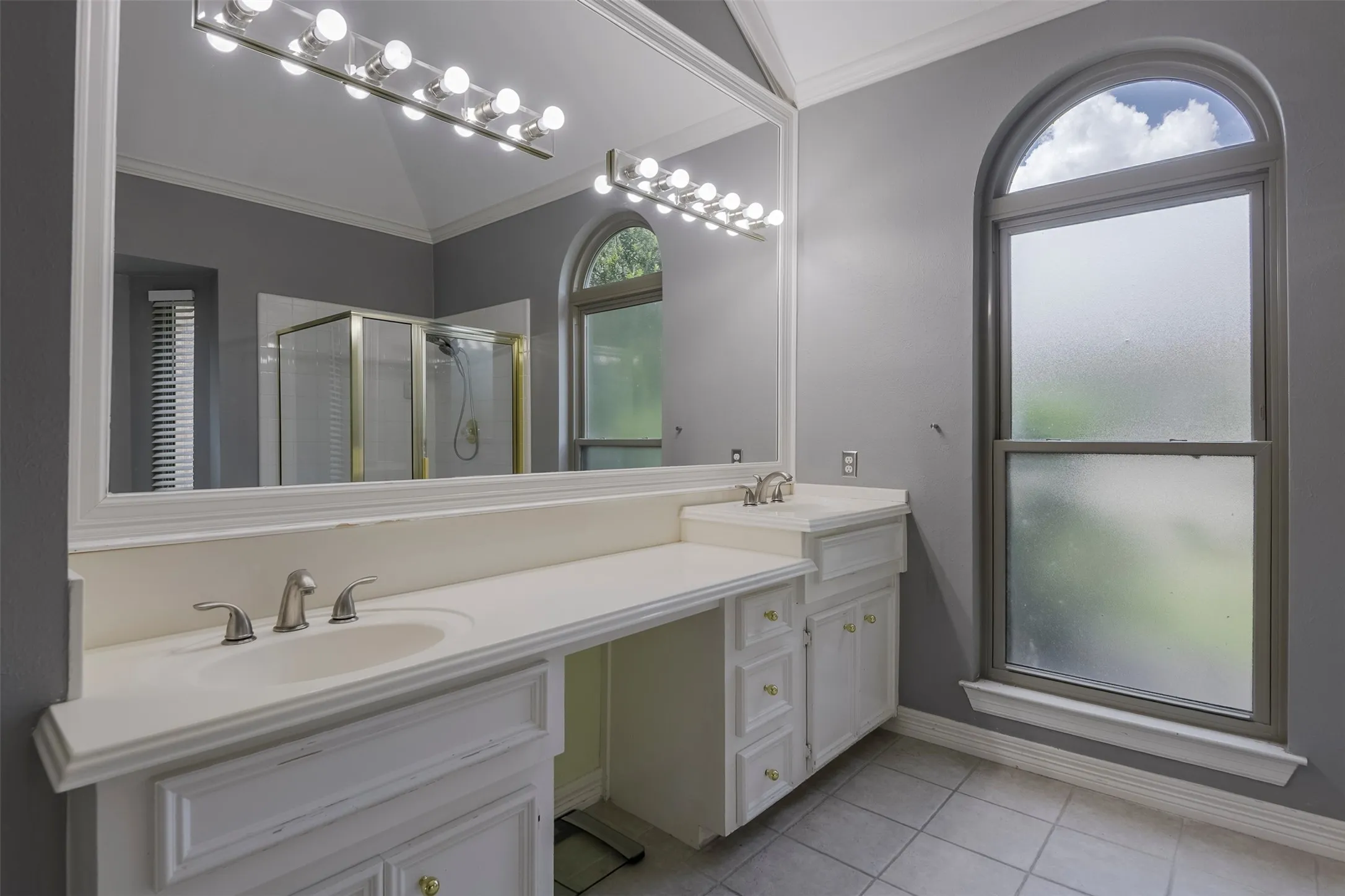 Dual vanity with integrated sinks, white cabinetry, and a large wall-mounted mirror