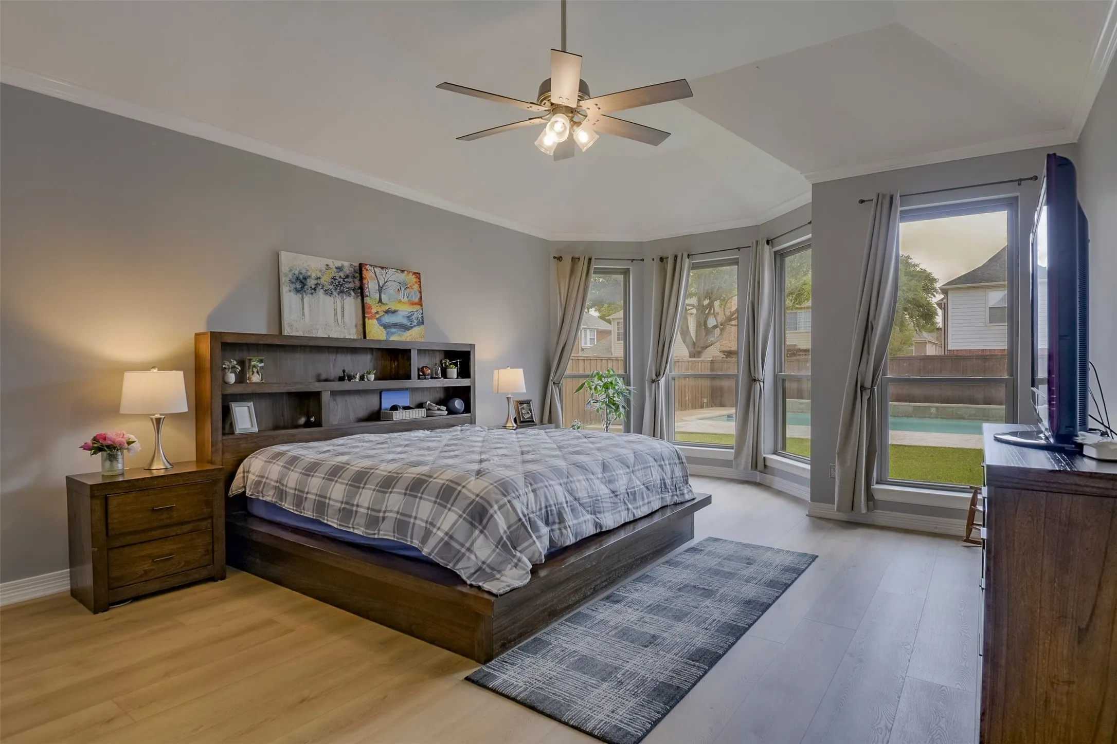 Hard-surface flooring, high ceilings, ceiling fan with light fixture, bay window, and crown molding