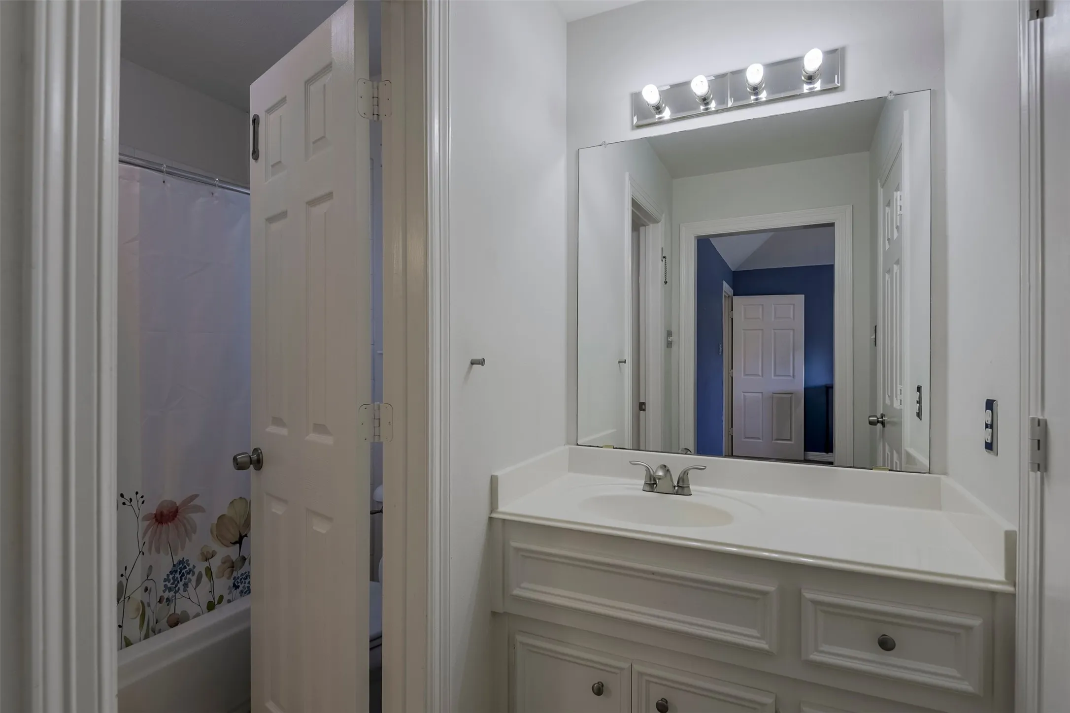 Vanity with an integrated sink, polished chrome faucet, and a large wall-mounted mirror