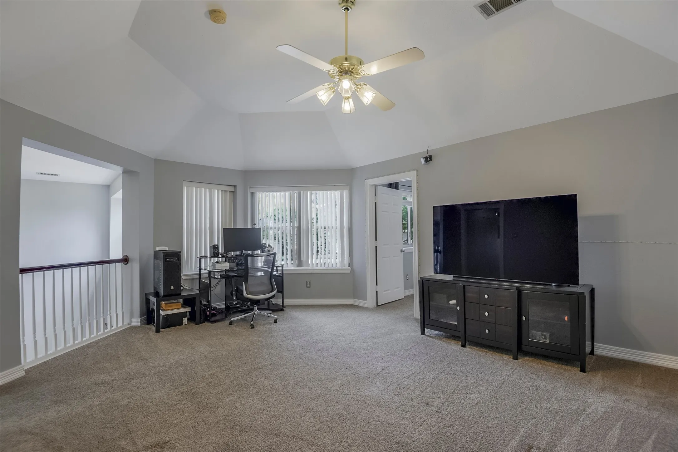 Carpeted room with vaulted ceiling and ceiling fan