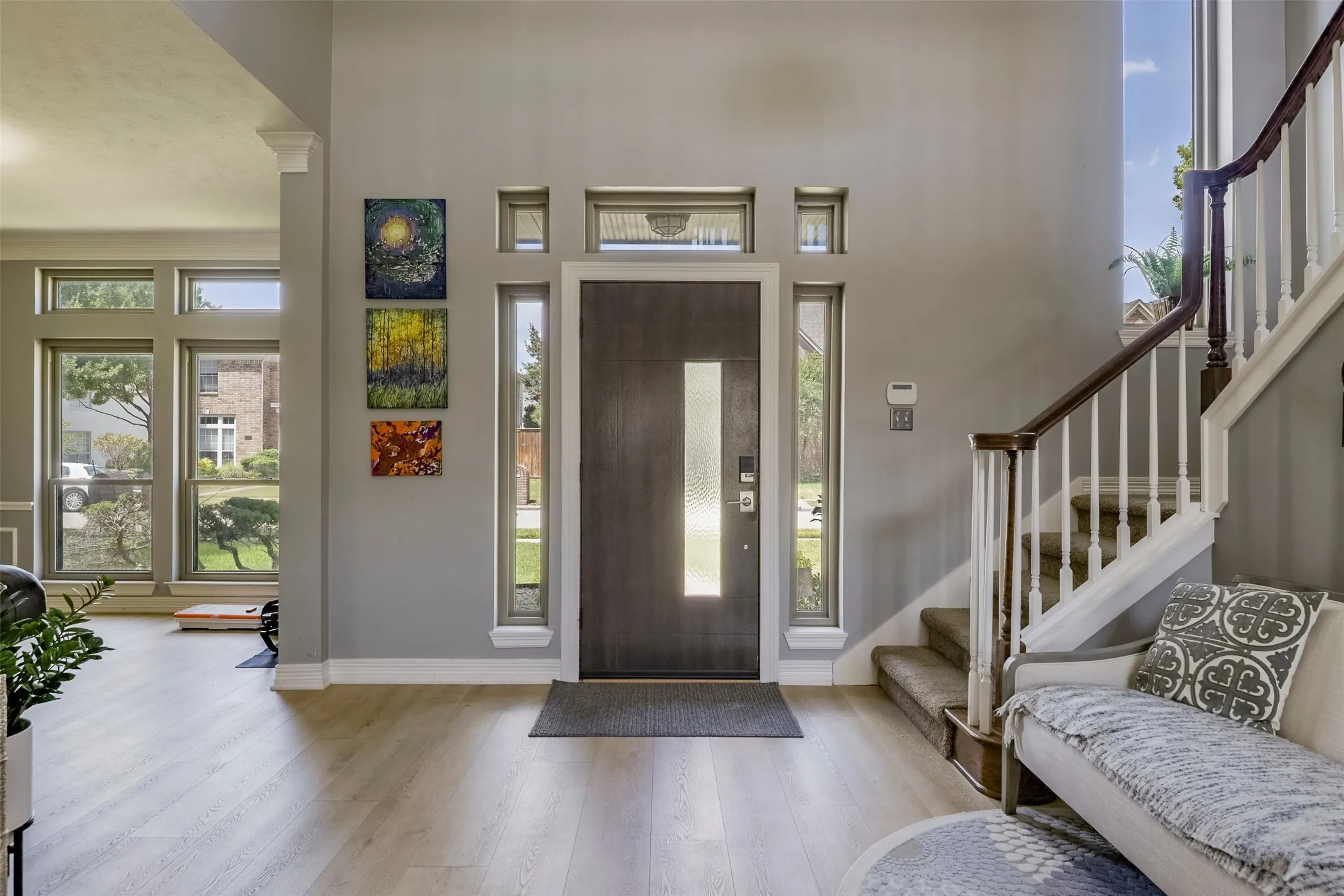 Two-story entryway featuring a dark wood-finish door with frosted glass insert, flanked by tall vertical windows and transom windows