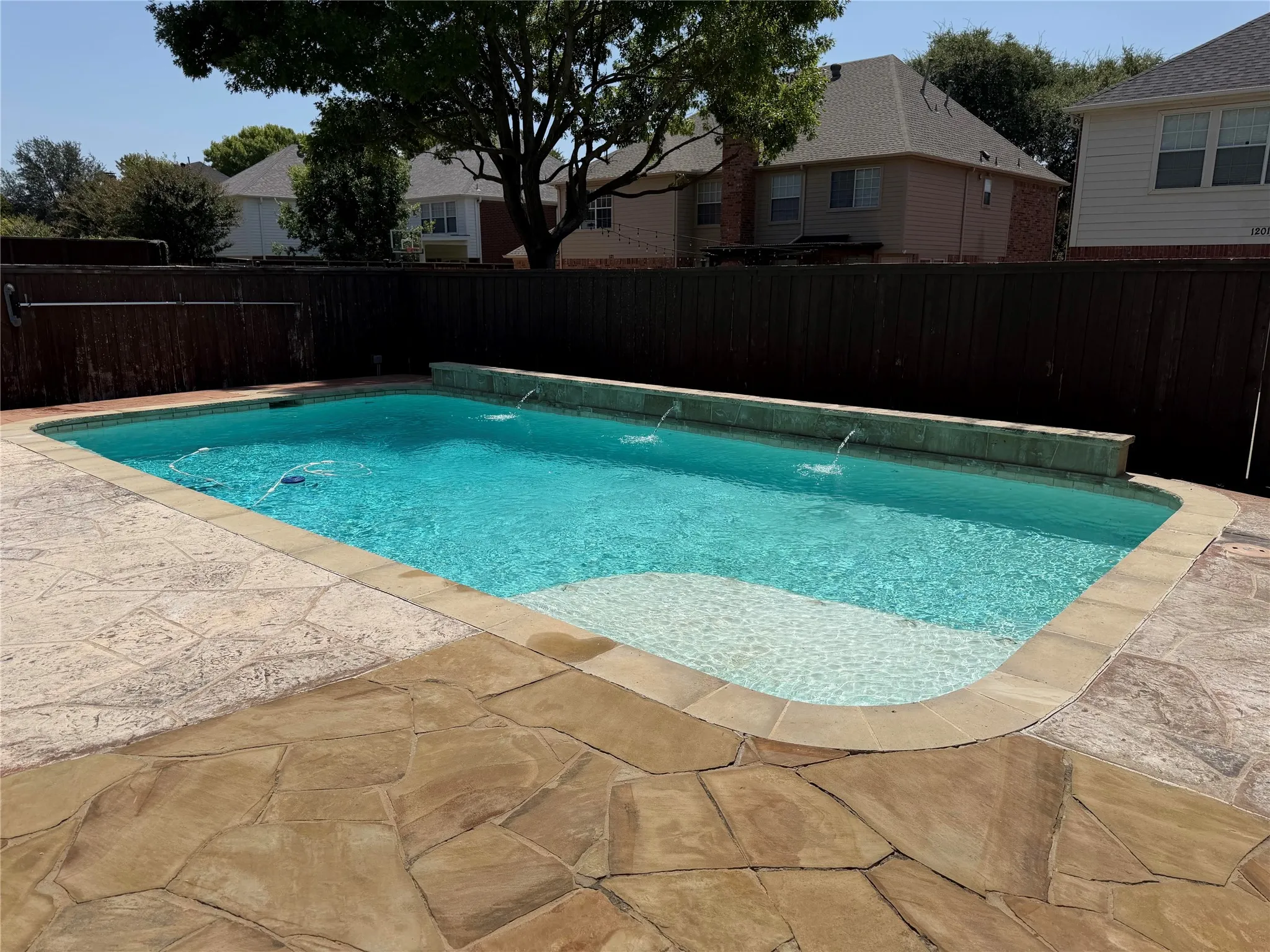 In-ground swimming pool with water features, integrated steps, and flagstone coping
