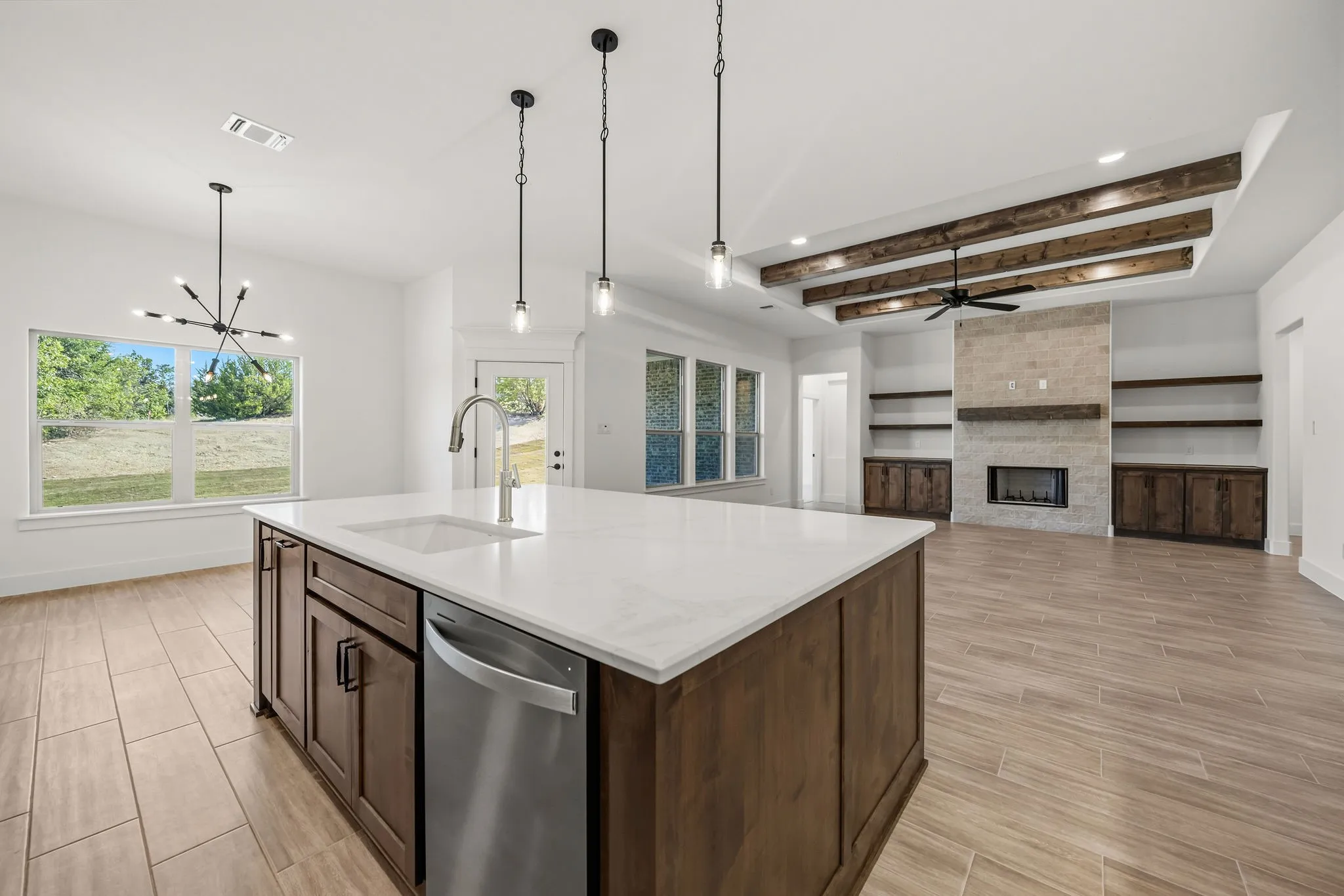 Spacious interior featuring a kitchen island with sink, stainless steel dishwasher, and quartz countertop