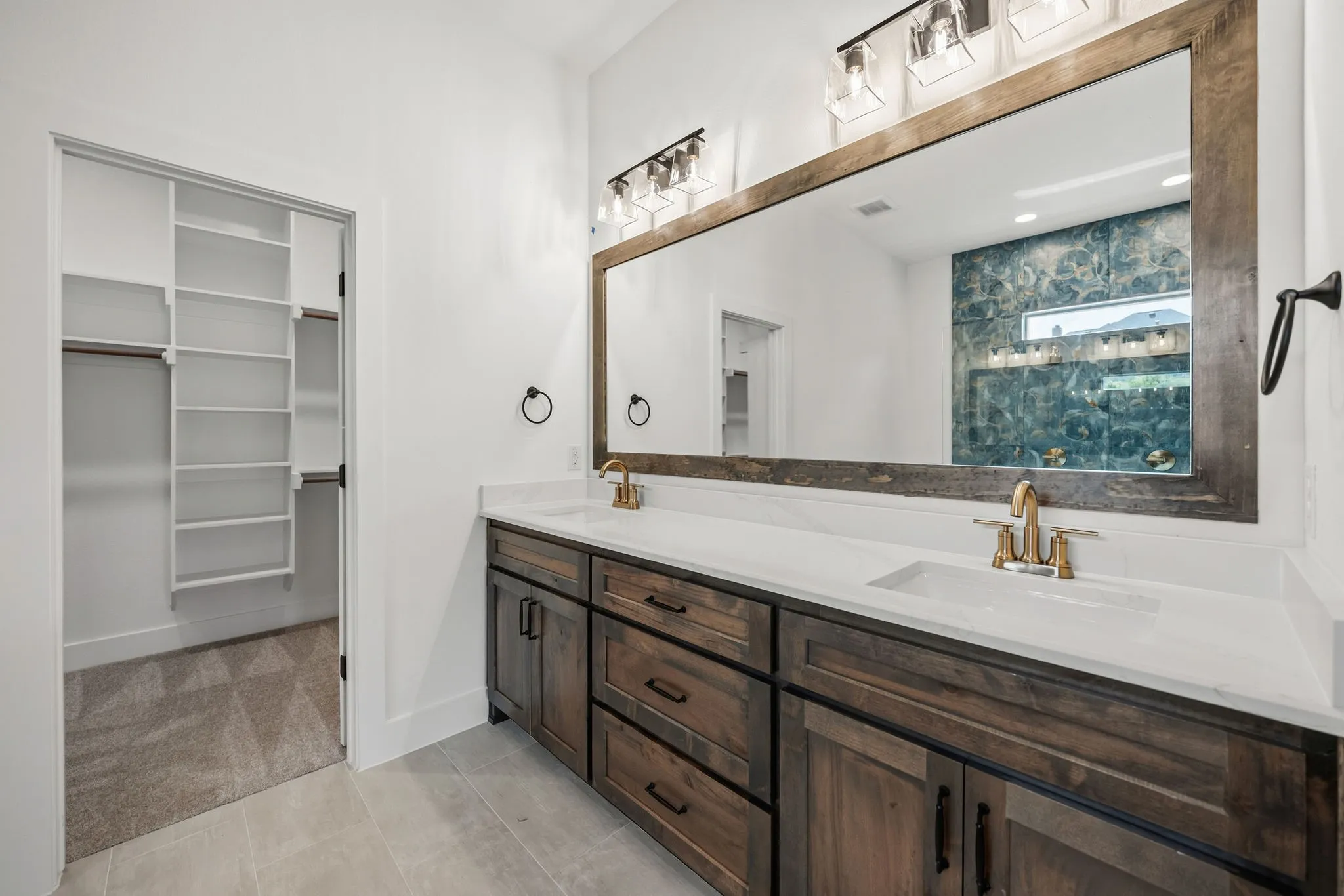 Dual vanity with wood-finish cabinetry, white countertops, and undermount sinks
