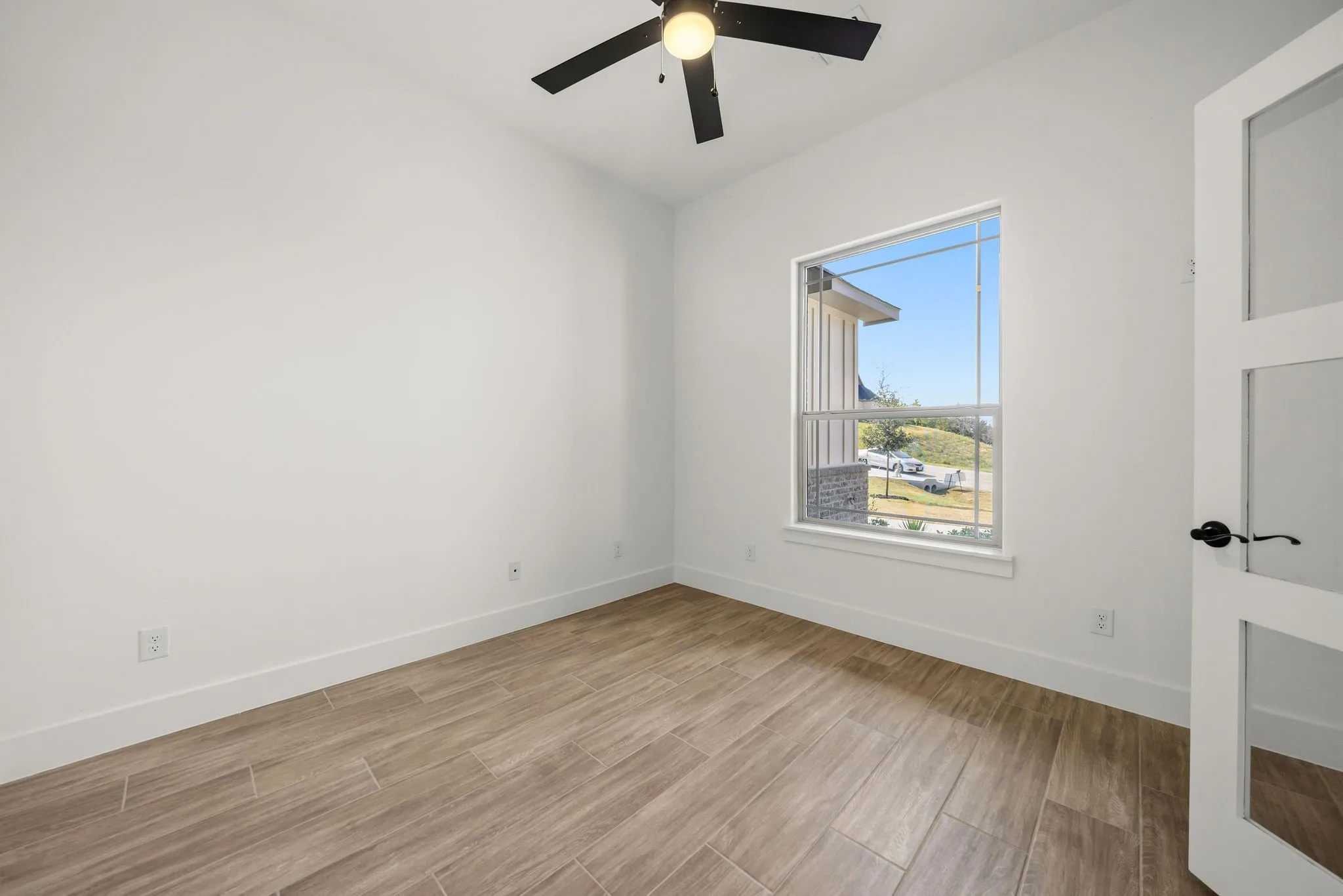 Wood-finish flooring, white walls, and a window with exterior residential elements
