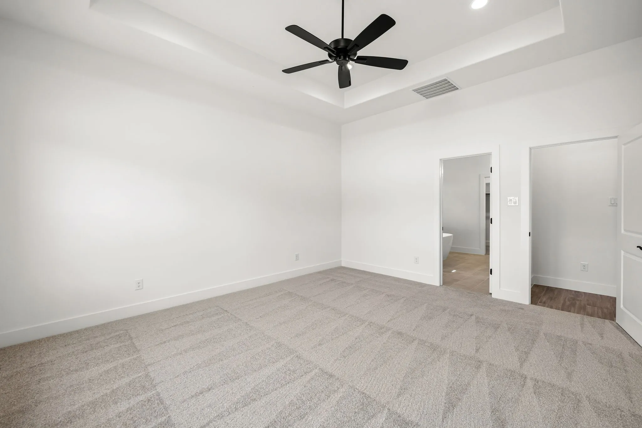 Recessed ceiling with an integrated ceiling fan, light gray carpet flooring, white walls, and white trim