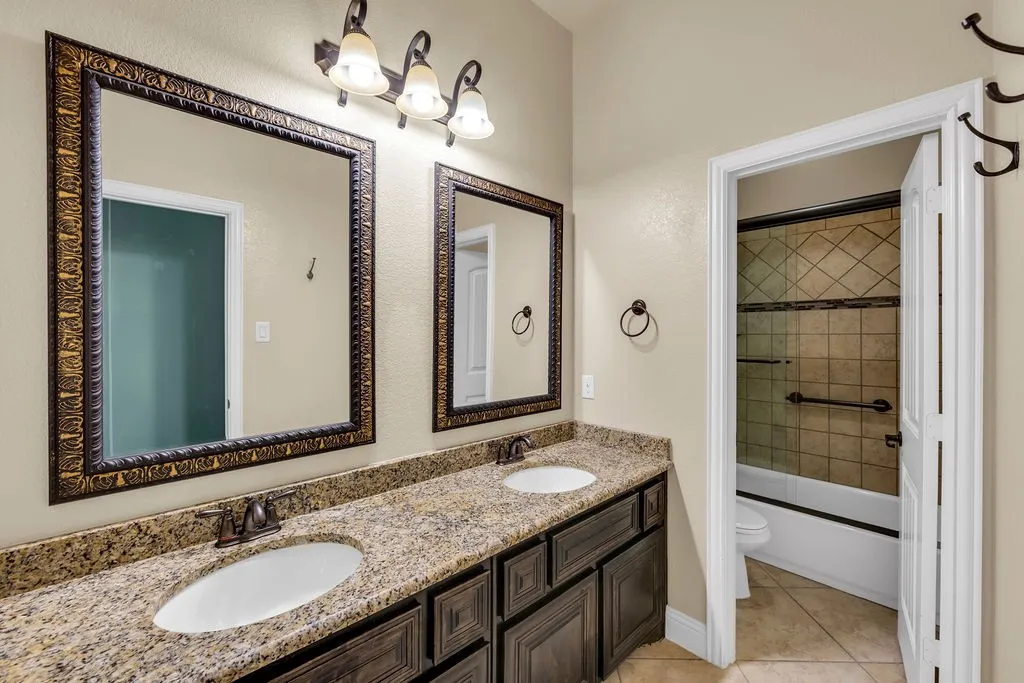 Dual vanity with stone-finish countertop and dark wood-finish cabinetry