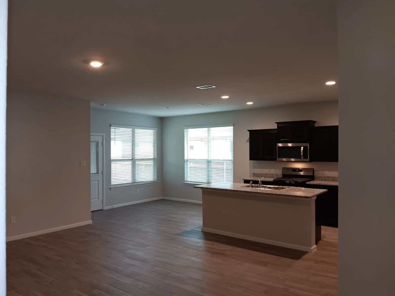 Open-concept living area with wood-finish flooring, recessed lighting, and ample natural light from multiple windows