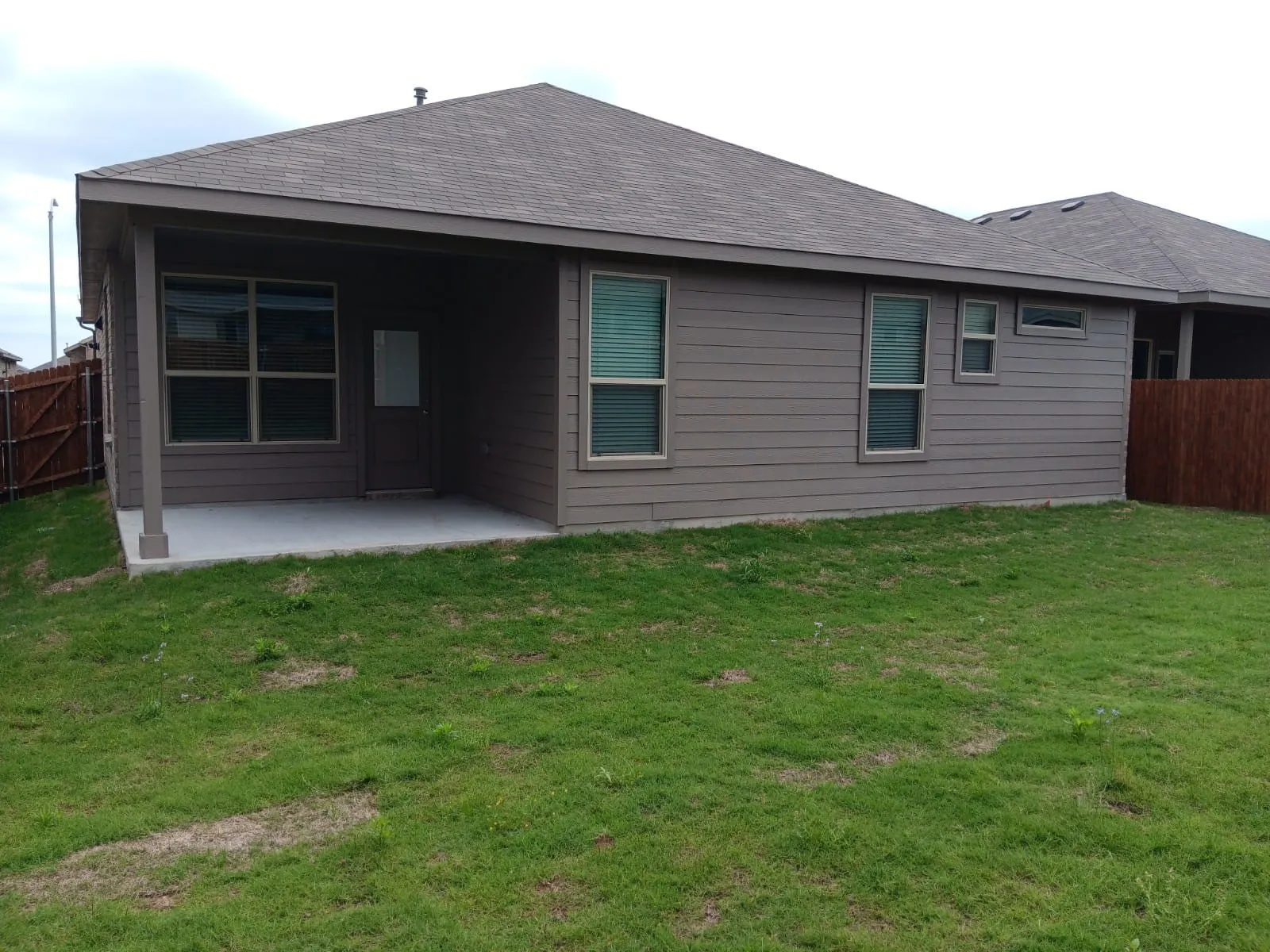 Pitched roofline, covered concrete patio, horizontal siding exterior, and multiple windows