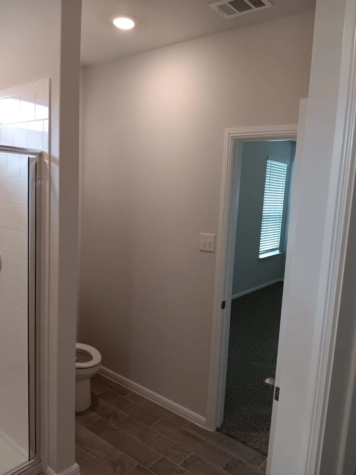 Recessed ceiling lighting, wood-finish flooring, white baseboards, and a white toilet