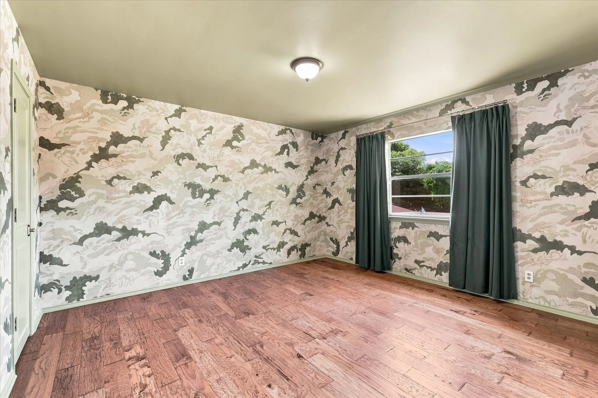 The second-story primary bedroom features beautiful Swedish wallpaper, wood floors, a walk-in closet, and an ensuite bath with vintage cabinetry.
