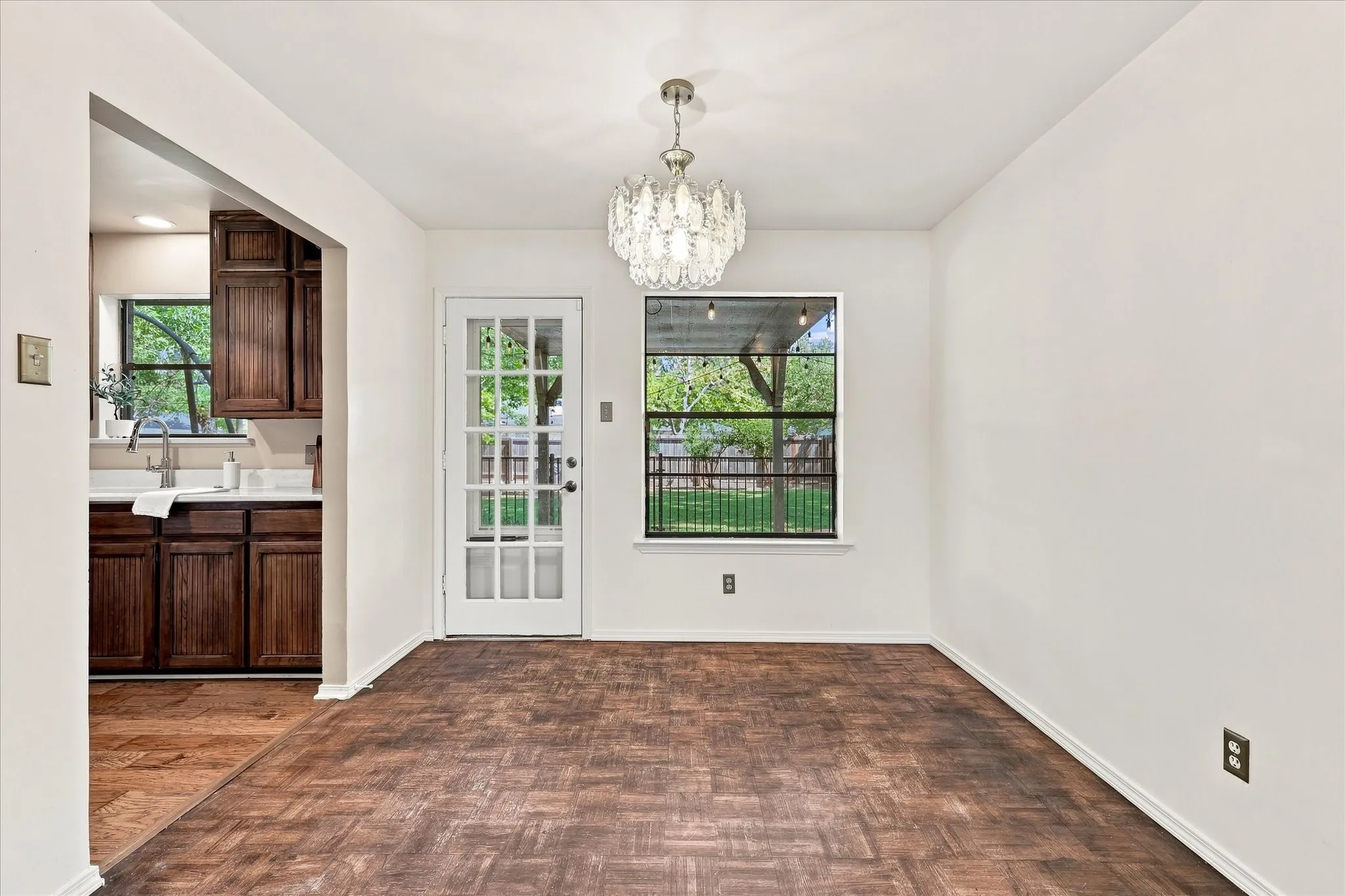 The dining room features parquet floors, a beautiful chandelier, and easy access to the kitchen and back yard.