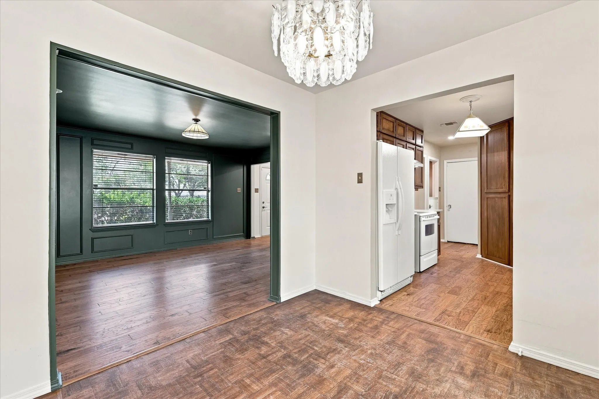 The dining room features parquet floors, a beautiful chandelier, and easy access to the kitchen and back yard.