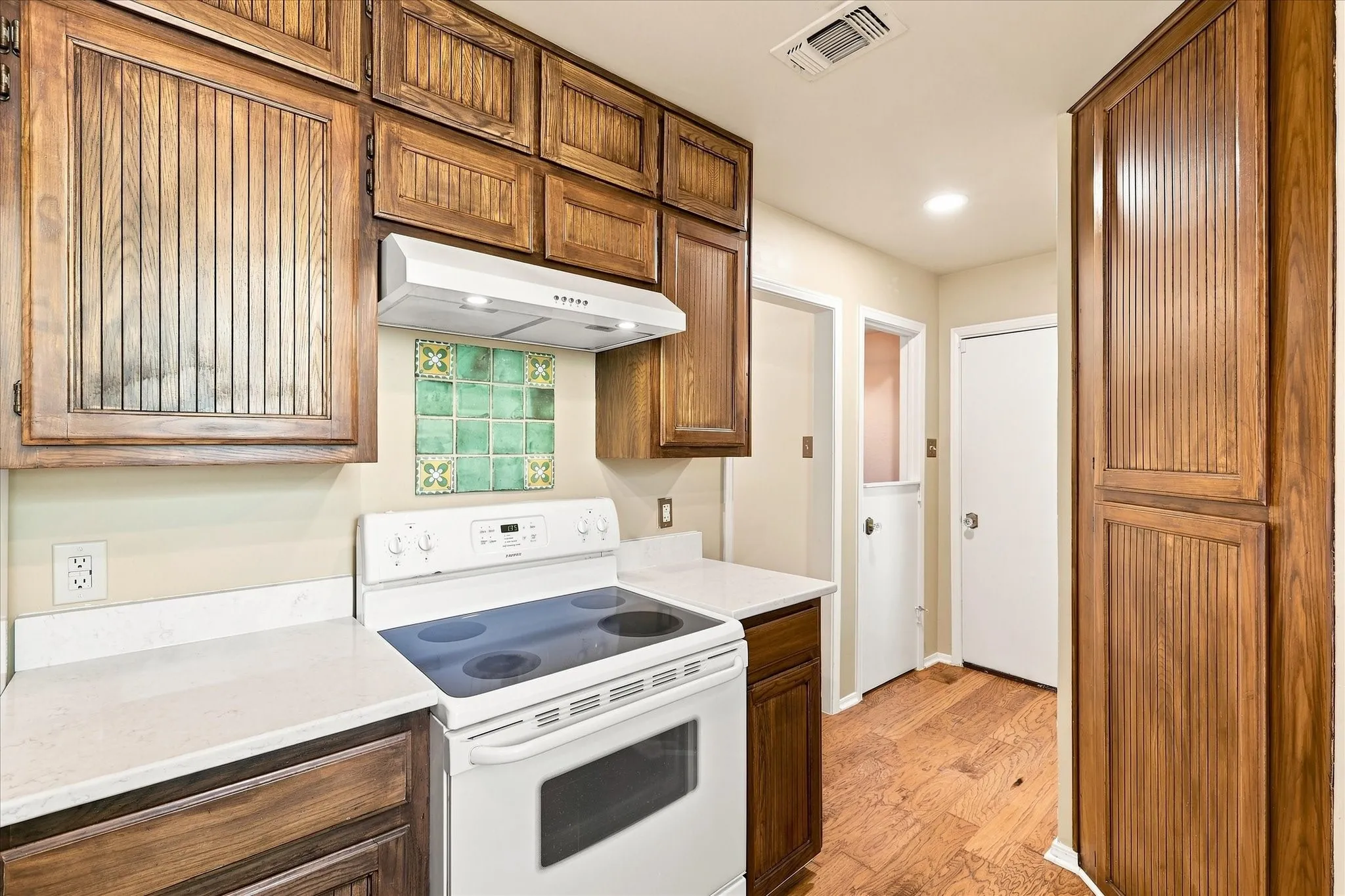 The kitchen features ceiling-height cabinets, marble countertops, a Kohler sink, vintage tile backsplash behind the range and recently replaced dishwasher and garbage disposal.