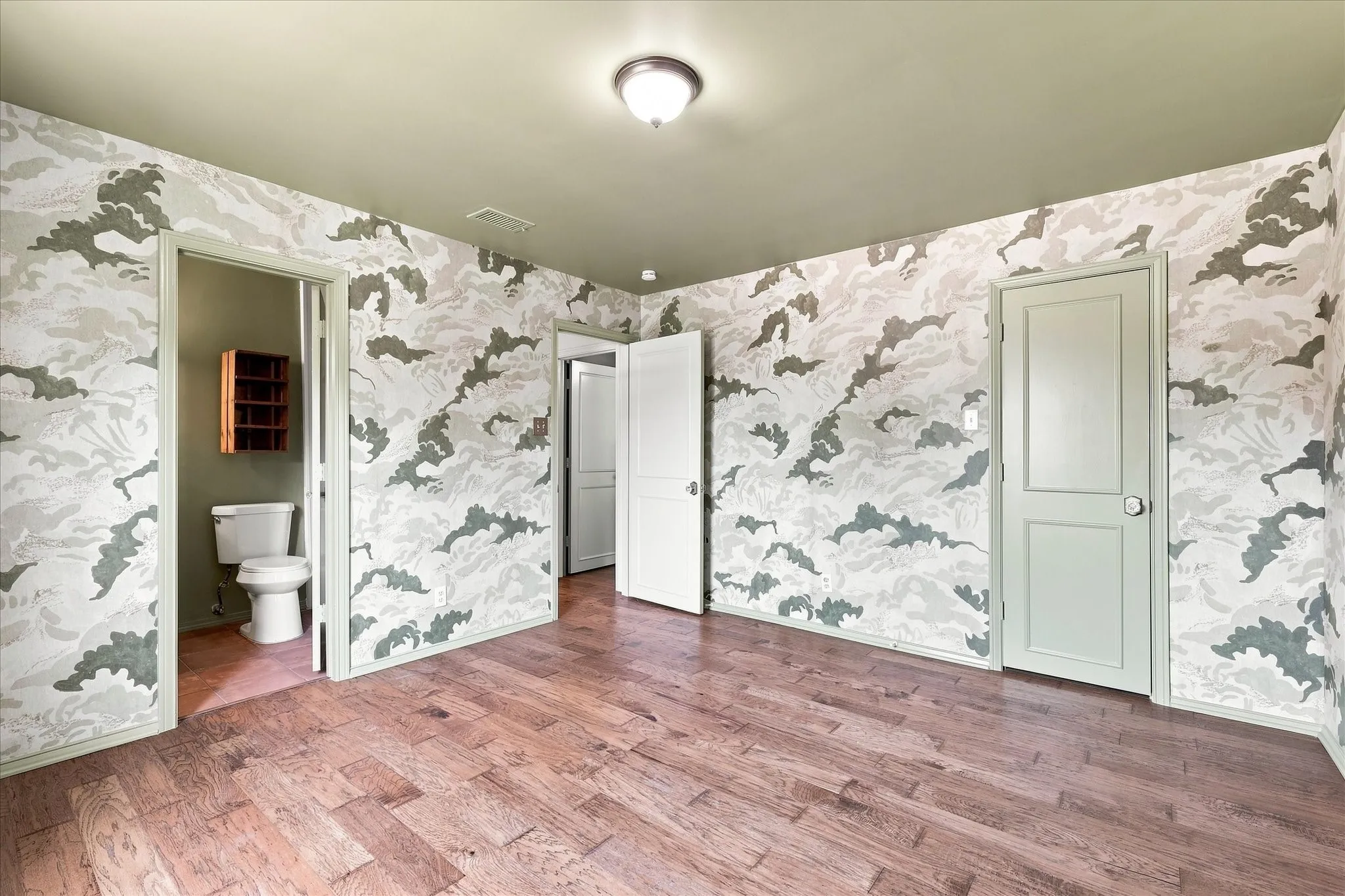 The second-story primary bedroom features beautiful Swedish wallpaper, wood floors, a walk-in closet, and an ensuite bath with vintage cabinetry.