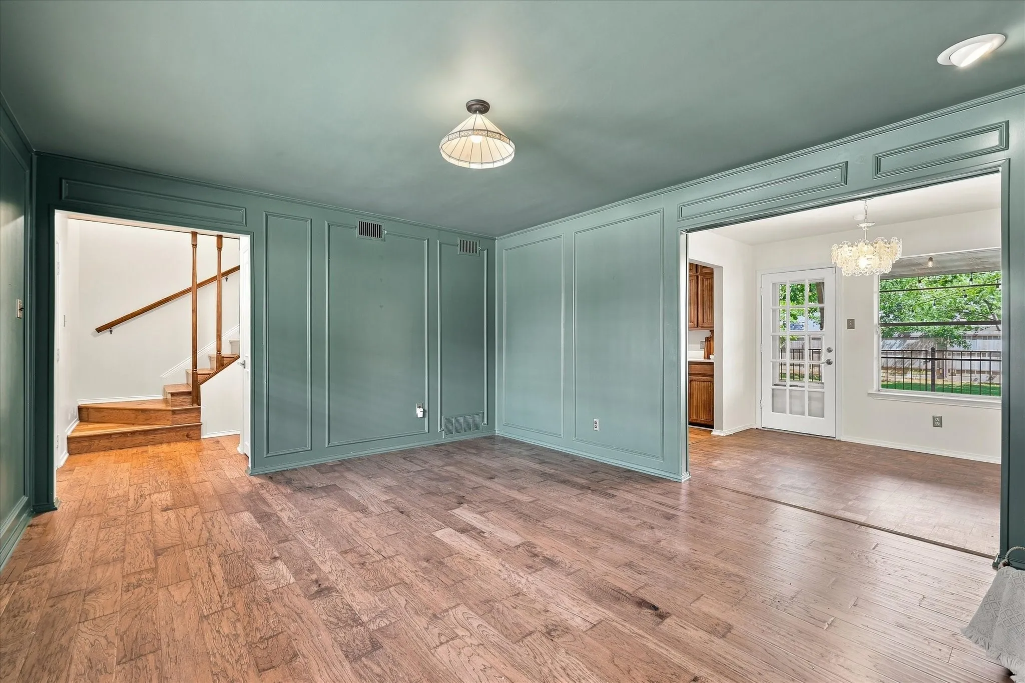 The living room features beautiful wood floors and on-trend color-drenched paint. A brick wood-burning fireplace features a raised hearth and wood mantel.  Lots of natural light fills this cozy room from the front windows.