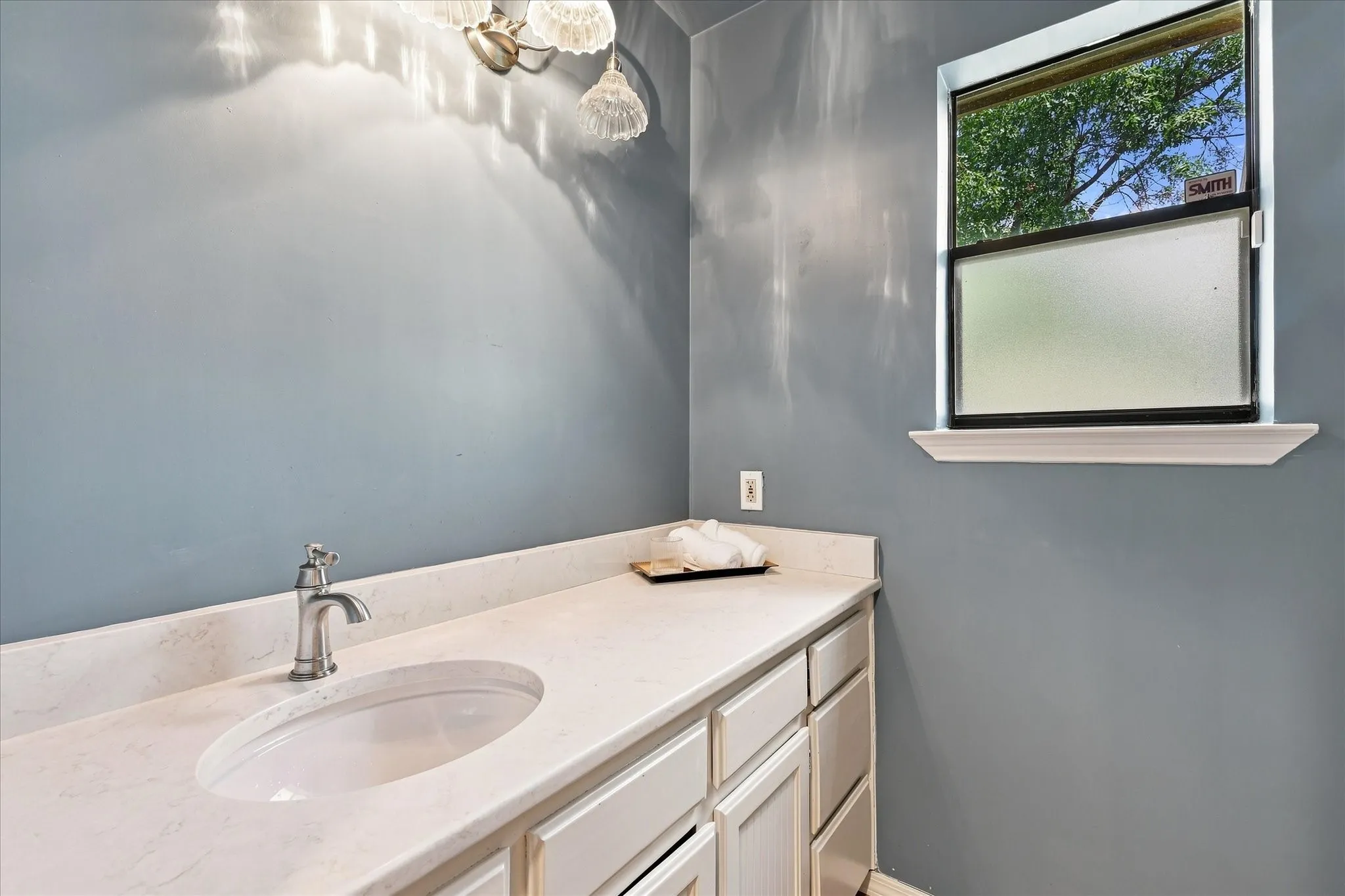 Downstairs half bath featuring vintage lighting  and marble countertops.
