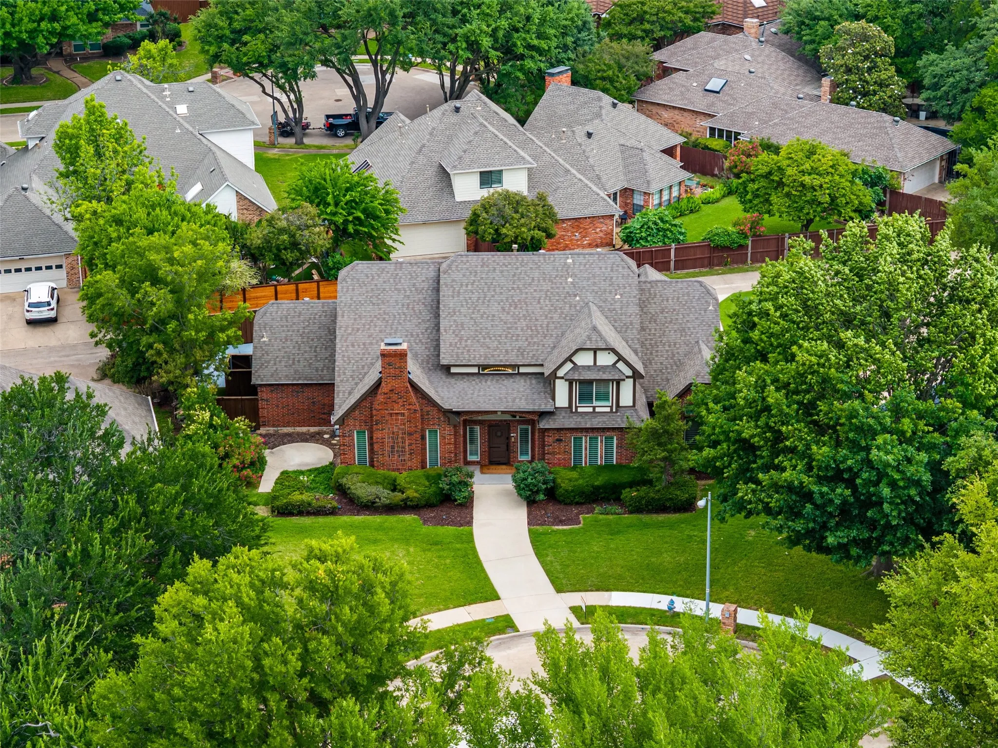 Brick exterior with a prominent chimney, a gabled roof, and a mature tree canopy