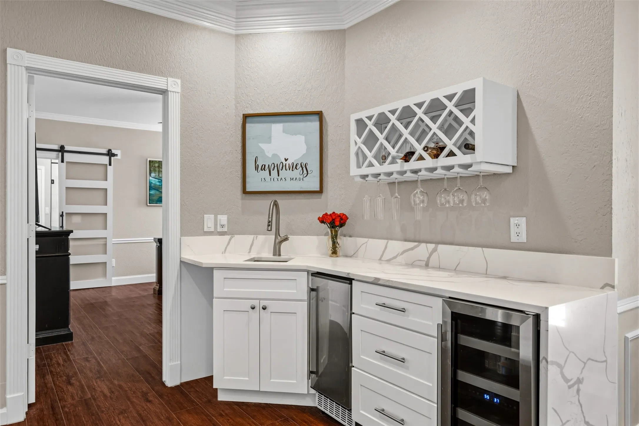 Built-in wet bar featuring a beverage cooler, wine refrigerator, and quartz countertops with a waterfall edge