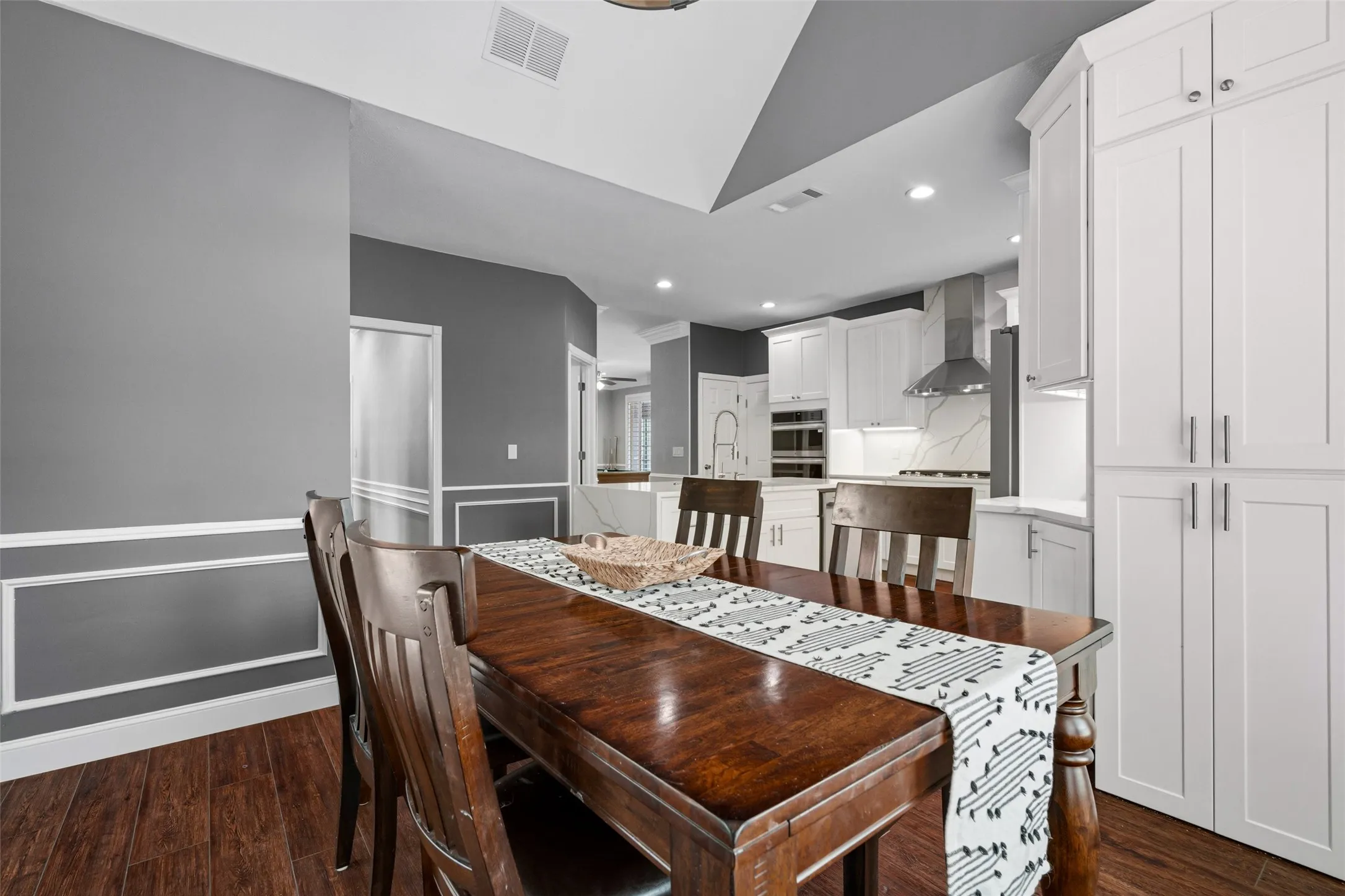 Wood-finish flooring, accent wall paneling, and a tray ceiling