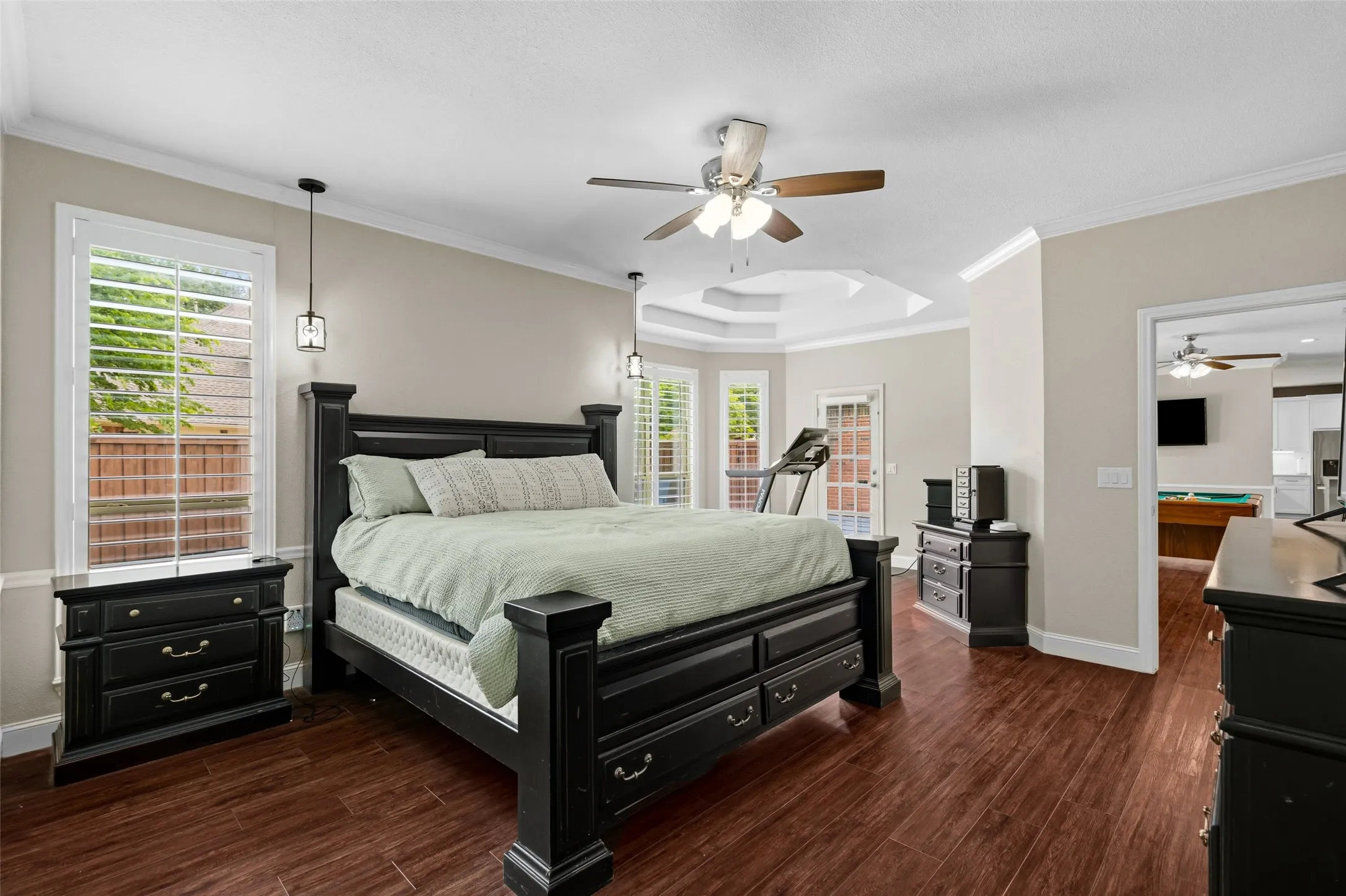 Wood-finish flooring, ceiling fan, crown molding, and tray ceiling
