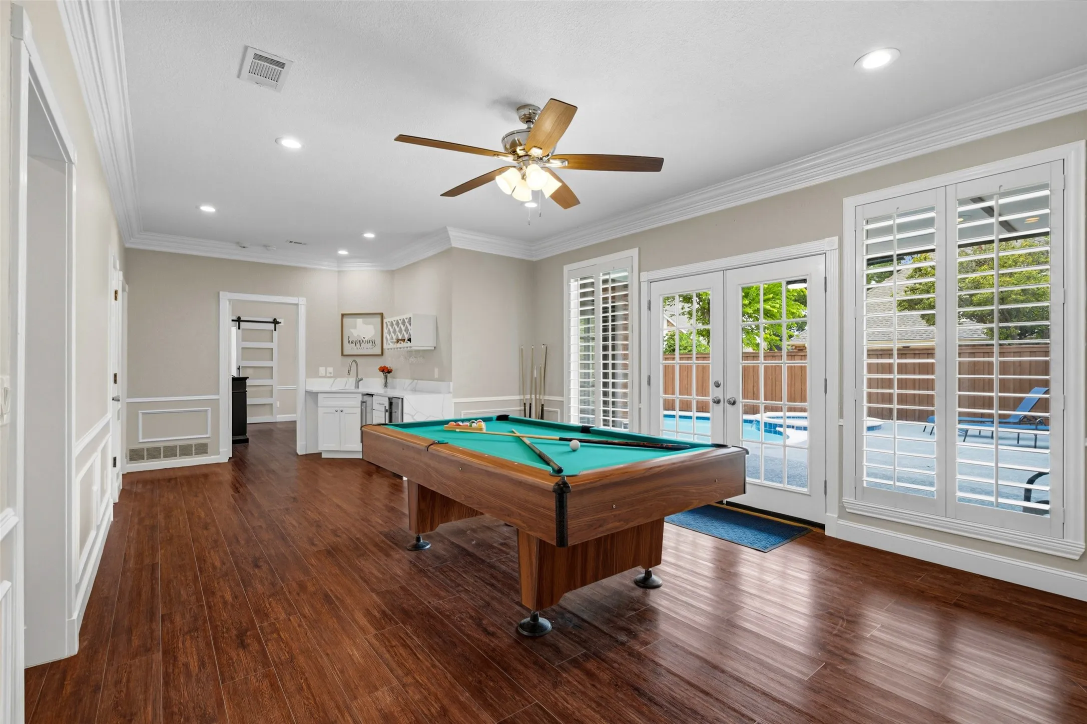 Recessed lighting, wood-finish flooring, built-in wet bar with sink, French doors, and a ceiling fan