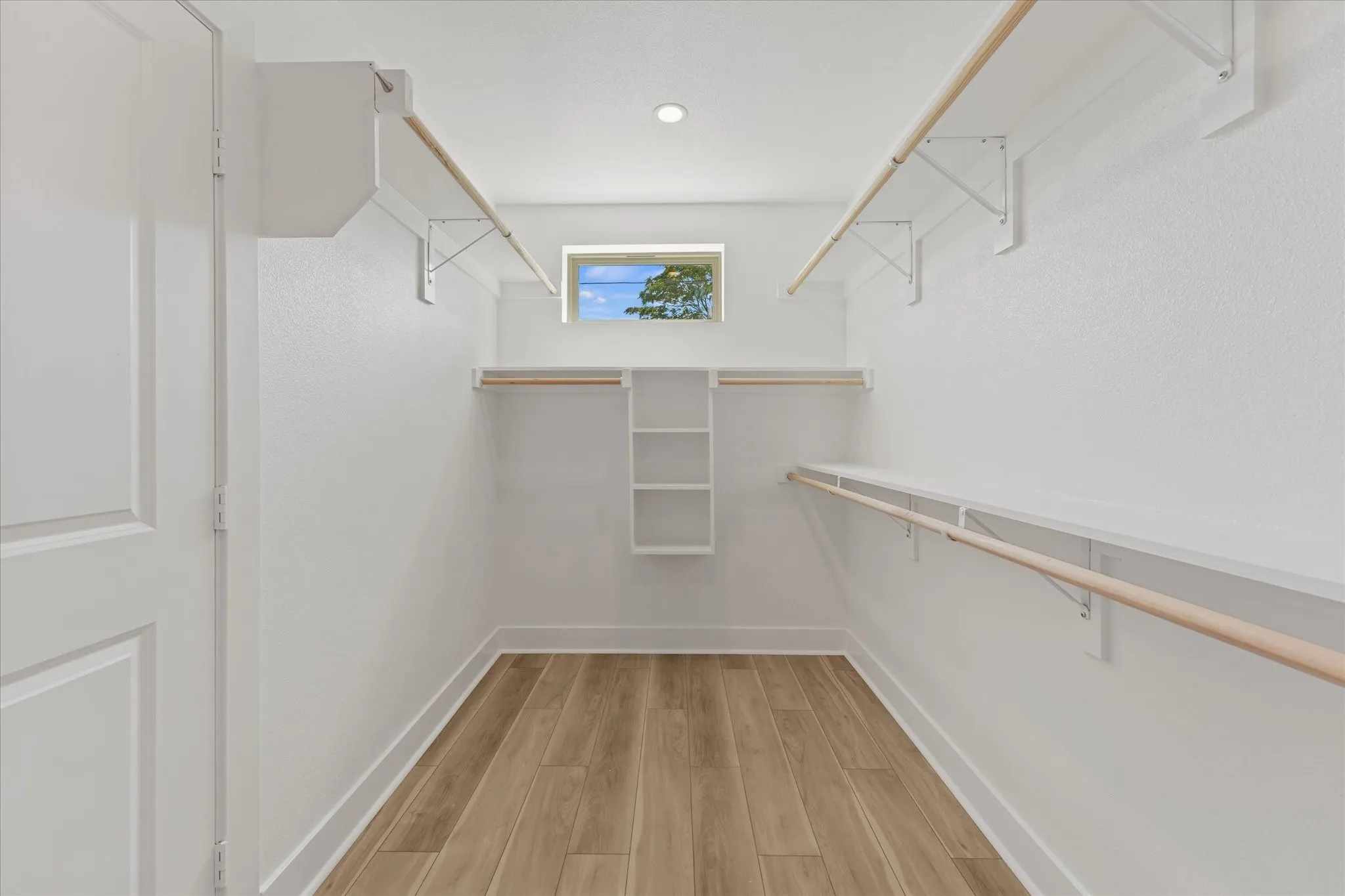 Walk-in closet with wood-finish flooring, recessed lighting, built-in shelving, and multiple hanging rods
