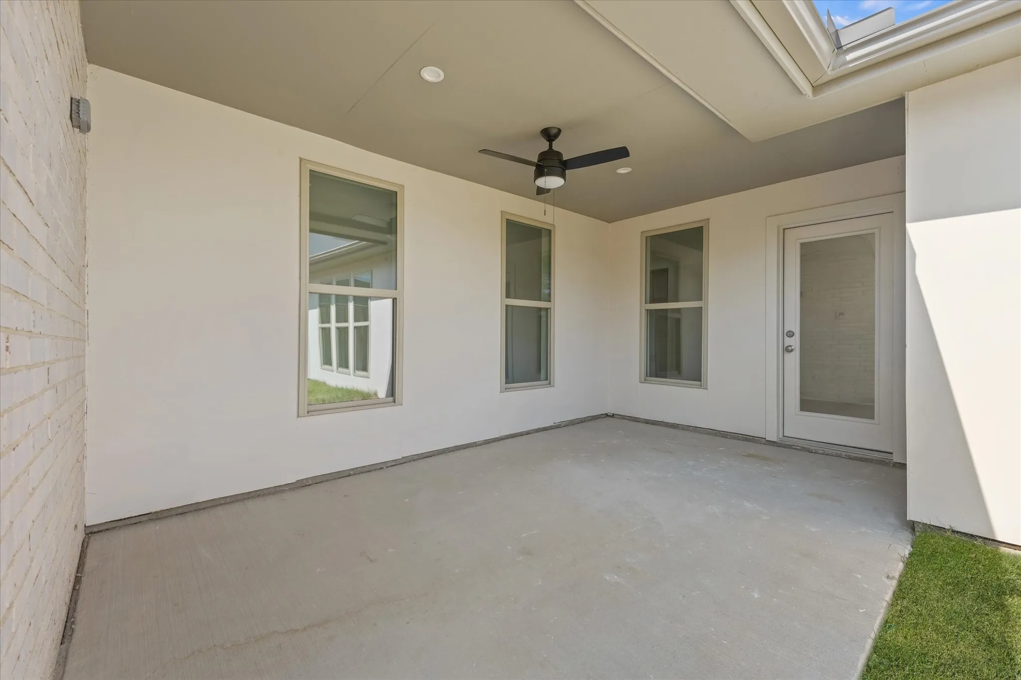Covered patio featuring a ceiling fan, recessed lighting, concrete flooring, and an exterior door with a full-light panel