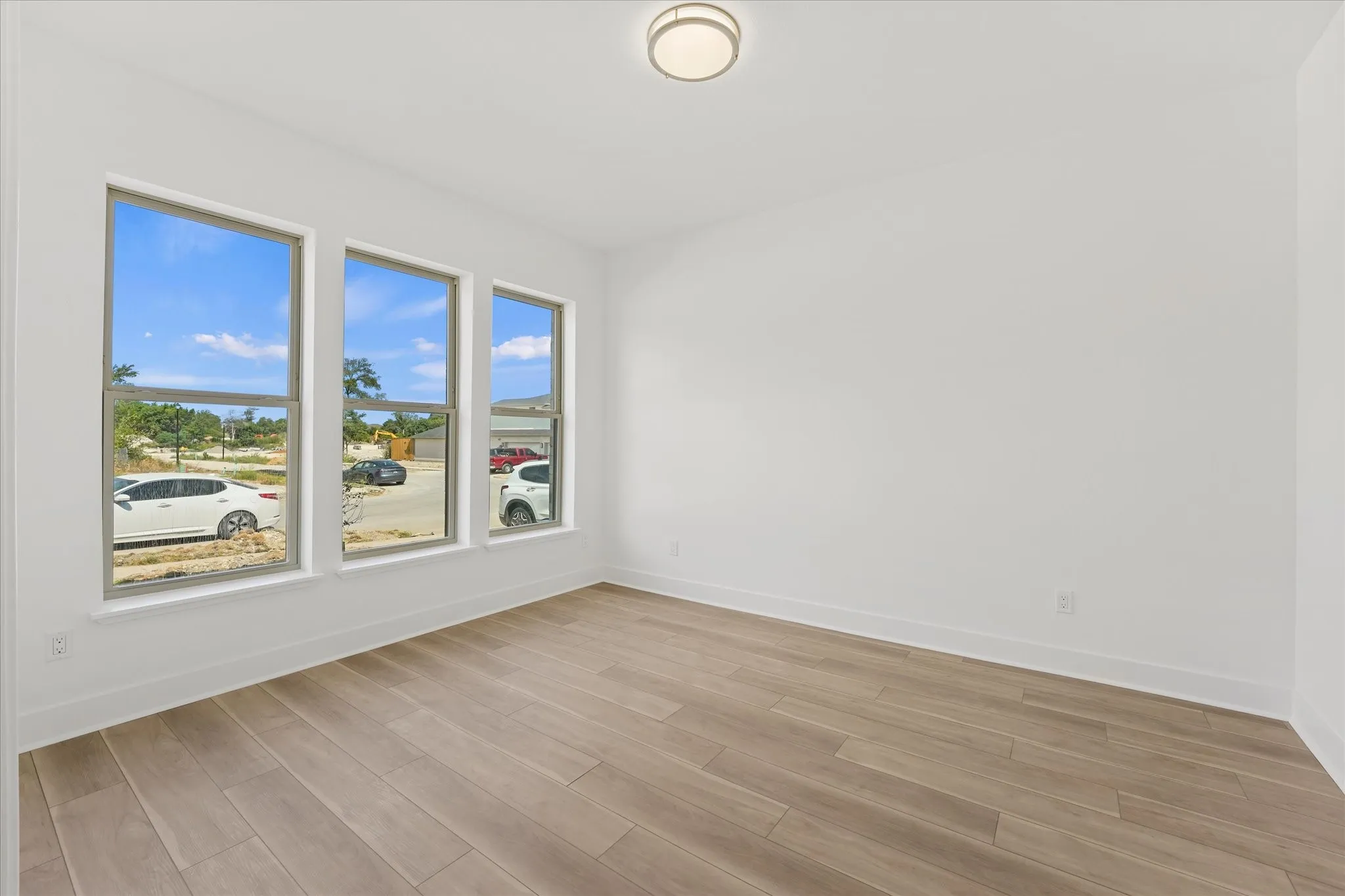 Wood-finish flooring, white walls, and a contemporary flush-mount ceiling light