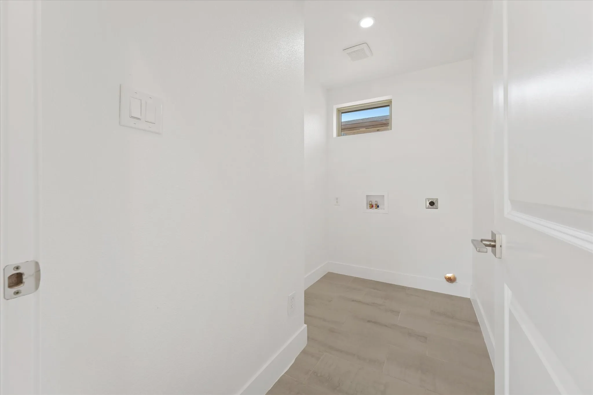 Utility room featuring light wood-finish flooring, a high window, and recessed ceiling lighting