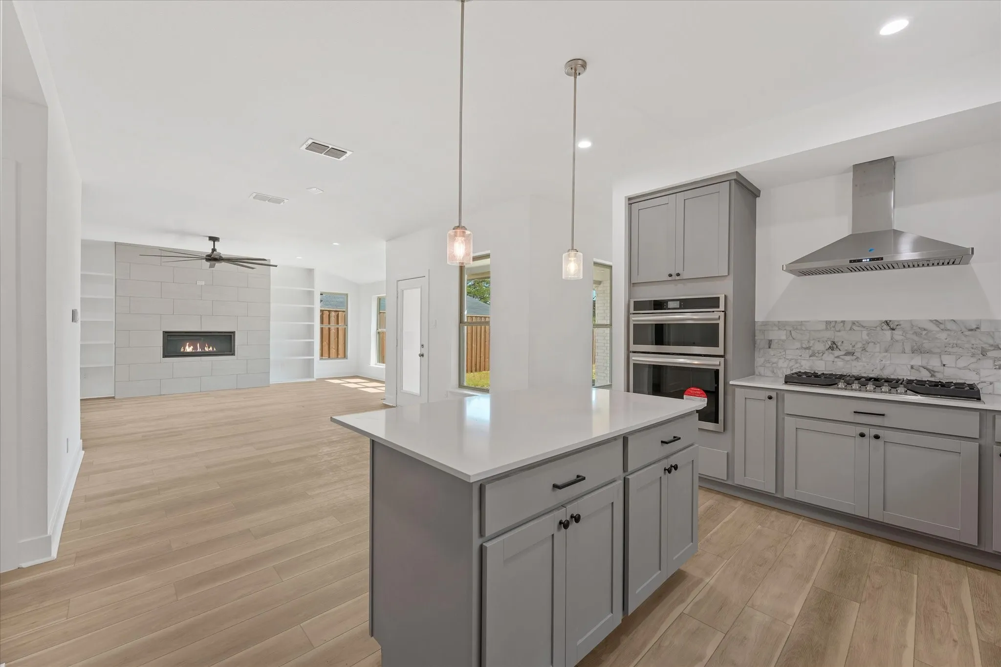 Gourmet kitchen with light gray cabinetry, stainless steel appliances, and a central island with a solid surface countertop